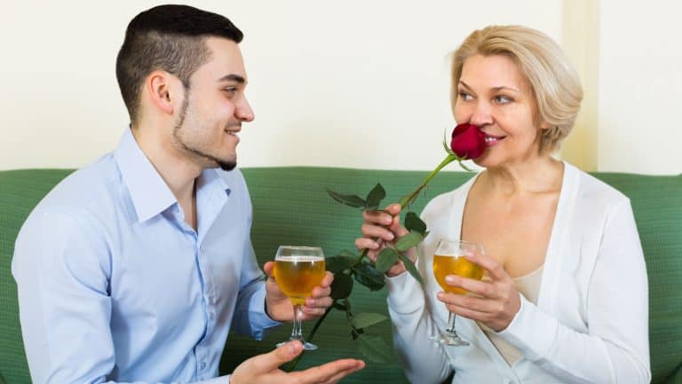 Adult son congratulating smiling mother and proposing a toast. Focus on guy