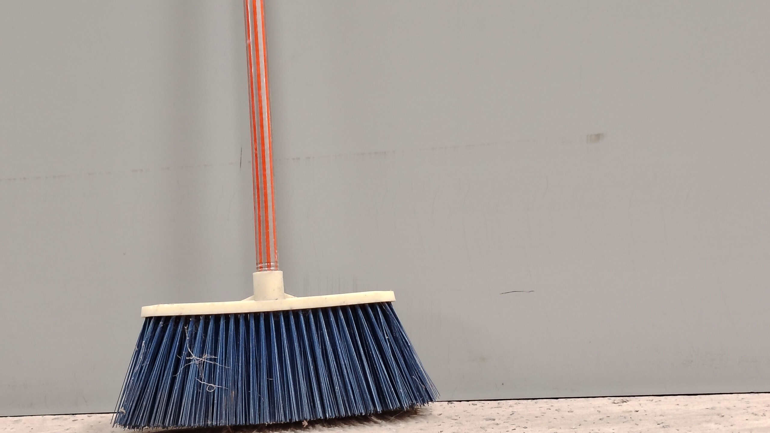 A Broom against a plain gray wall