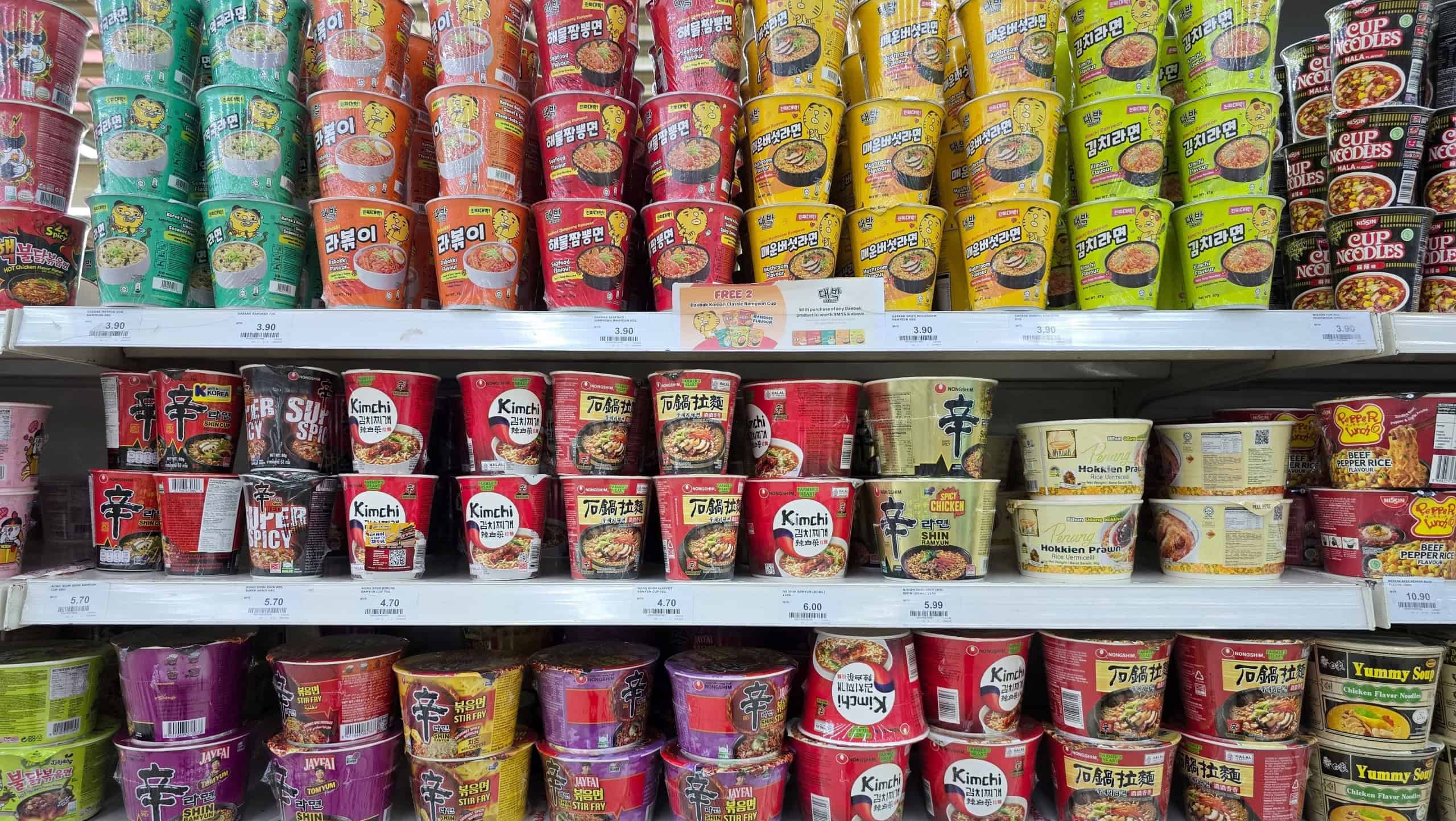 Penang, Malaysia – Sep 11, 2025: Colorful display of various instant cup noodles including Korean and Japanese brands such as Shin Ramyun, Kimchi and Cup Noodles, arranged on supermarket shelves.