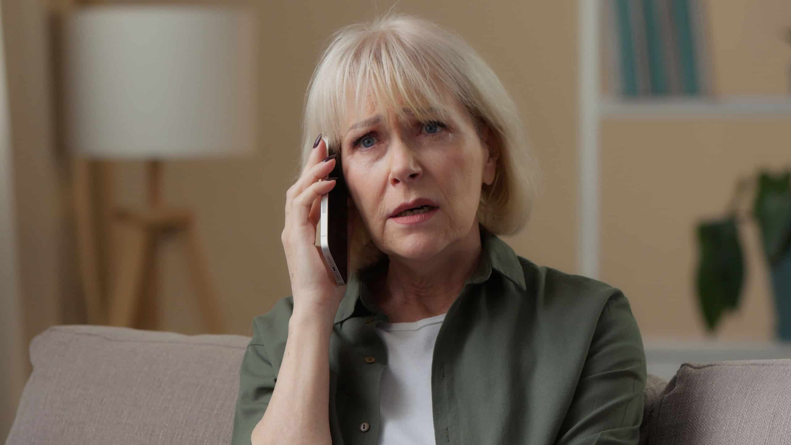 Confused sad Caucasian old woman talking mobile phone call negative conversation