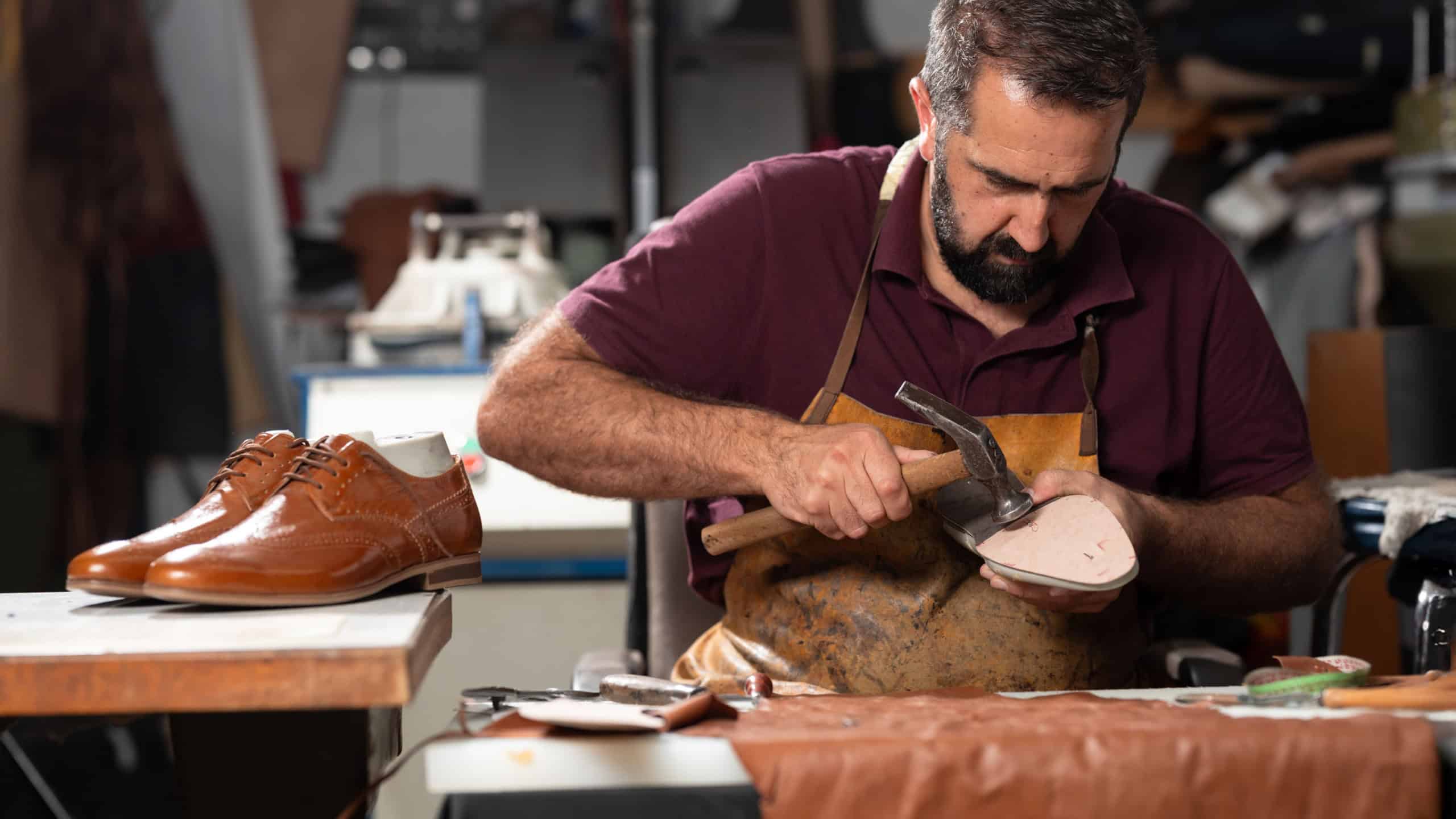 Cobbler at work repairing a leather shoe in a busy workshop