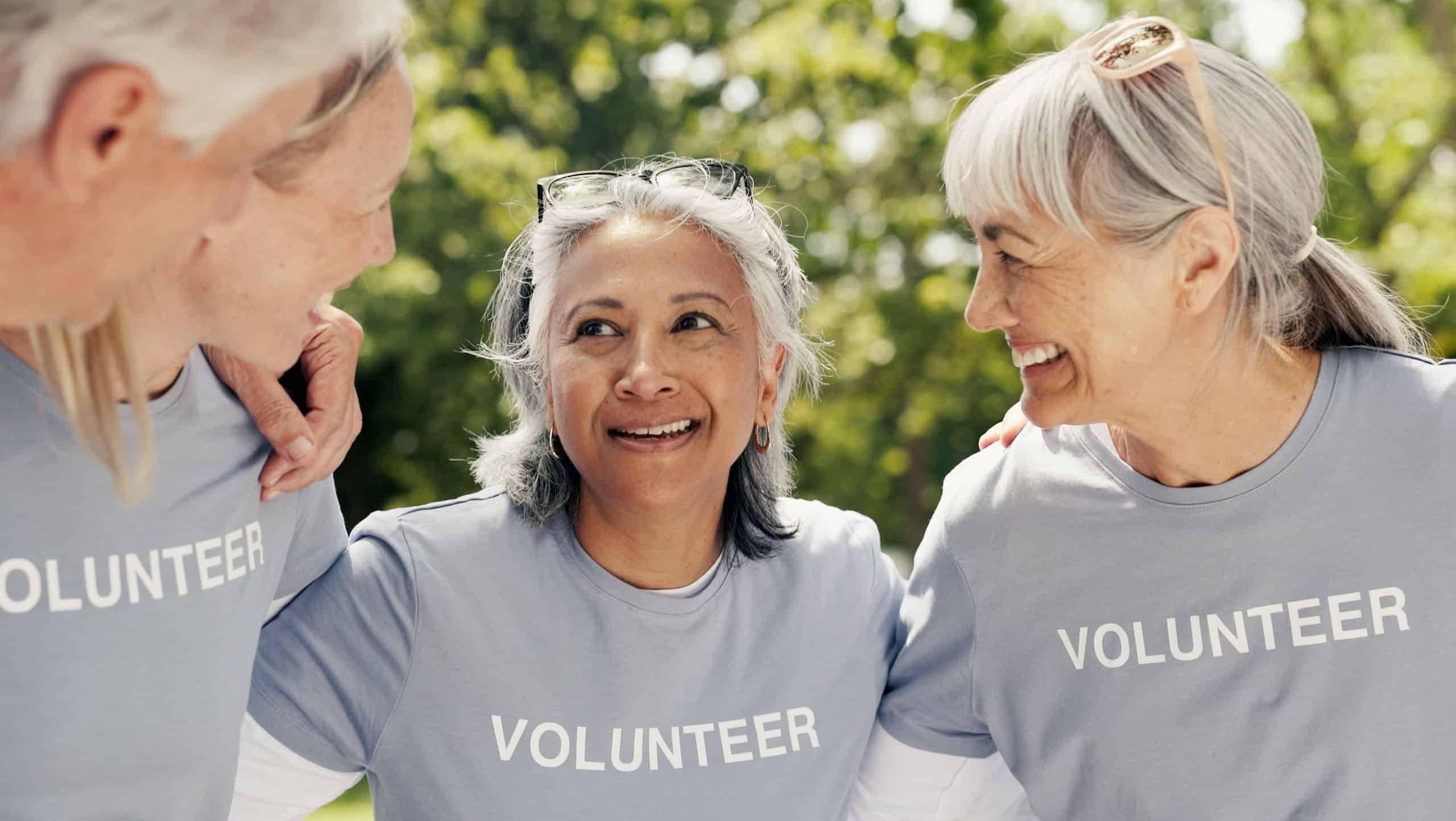 Old people, volunteer and huddle at park for community service, support and laugh together. Charity group, senior team and hug for collaboration, social responsibility and funny joke outdoor