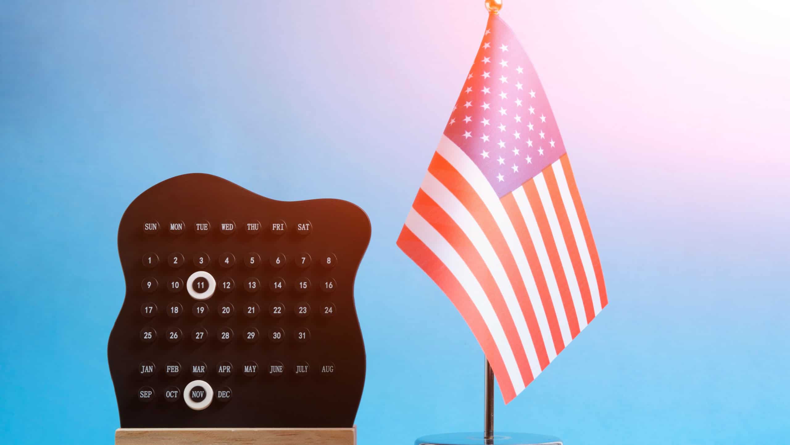 US flag and calendar with November 11 date on blue background for Veterans Day
