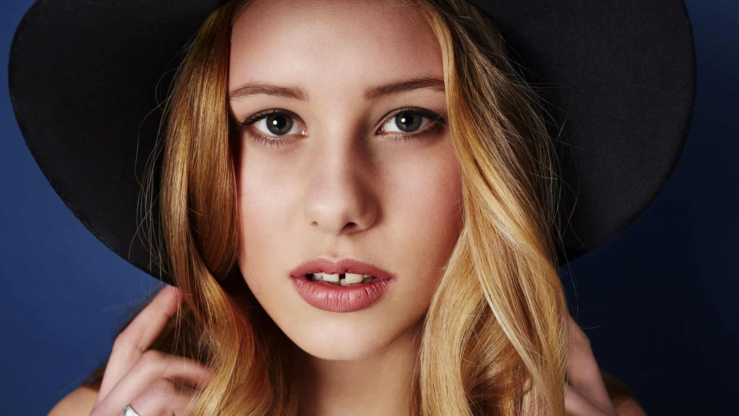 Portrait of model in fashionable hat with tooth gap
