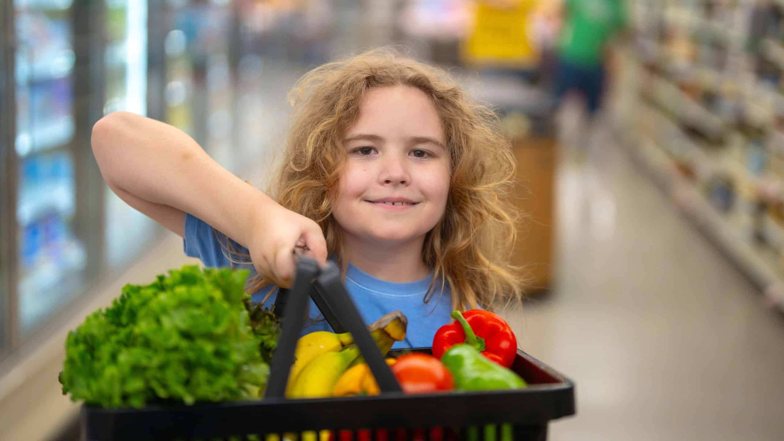 Child shopping for fresh vegetables and fruits at the supermarket.