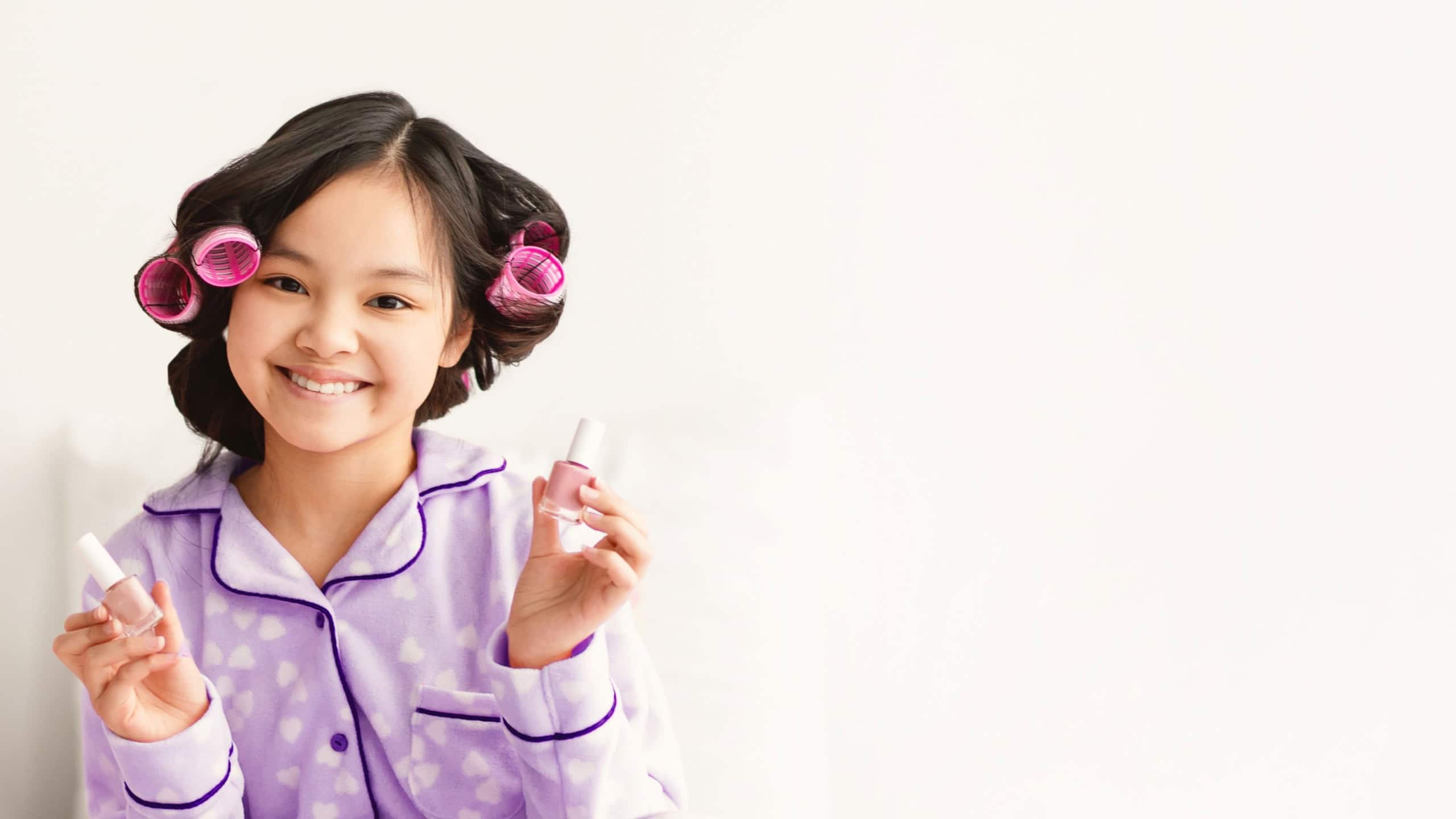 Girl With Hair Rollers Holding Nail Polish in Pajamas at Home in the Afternoon