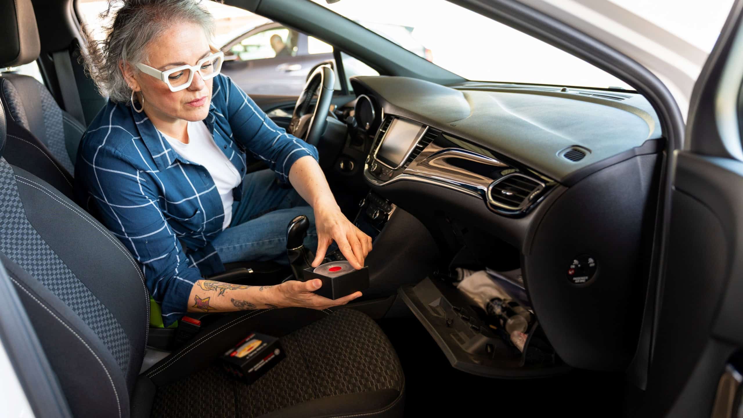 Woman organizing car storage, putting away a small box in the open glove compartment