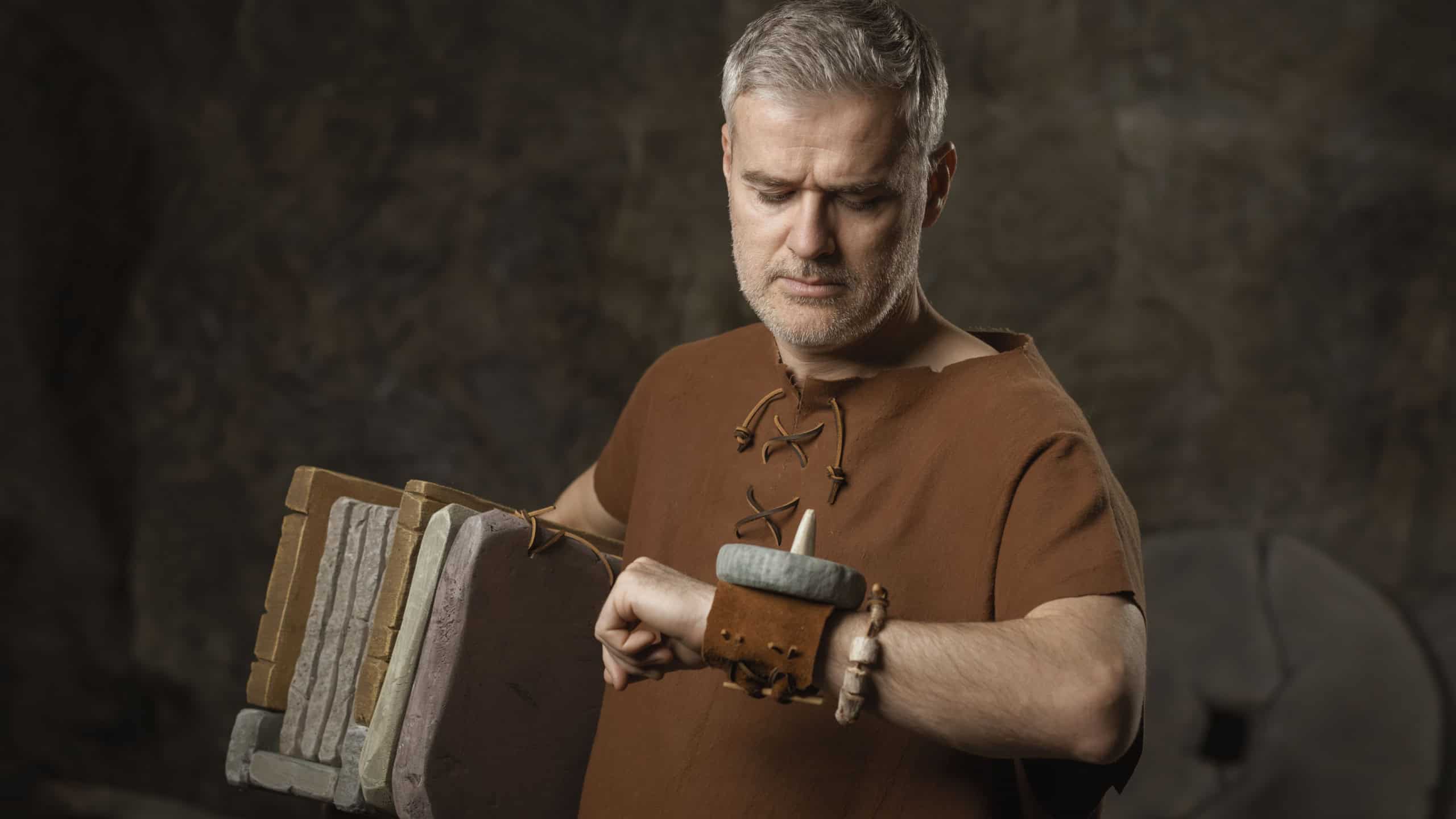 A humorous caveman employee in a cave, holding stone documents under his arm and checking the time on his stone wrist sundial, symbolizing office stress and ancient deadlines.