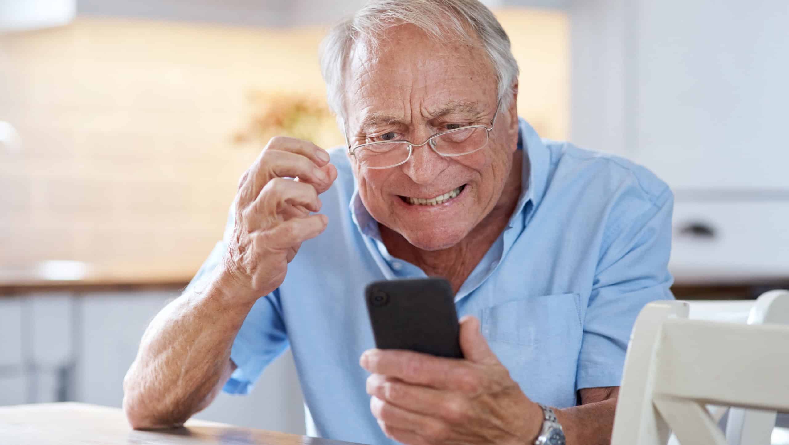 Senior, man and frustrated with phone in home for connection fail, 404 error or technical issue. Annoyed, elderly person and mobile stress in kitchen for low battery, network glitch and slow internet