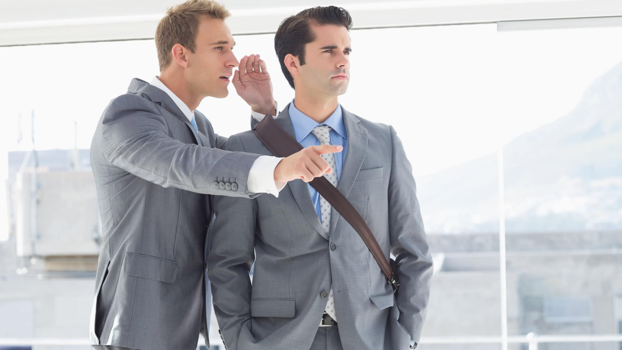 Businessman telling secret to his colleague in the office