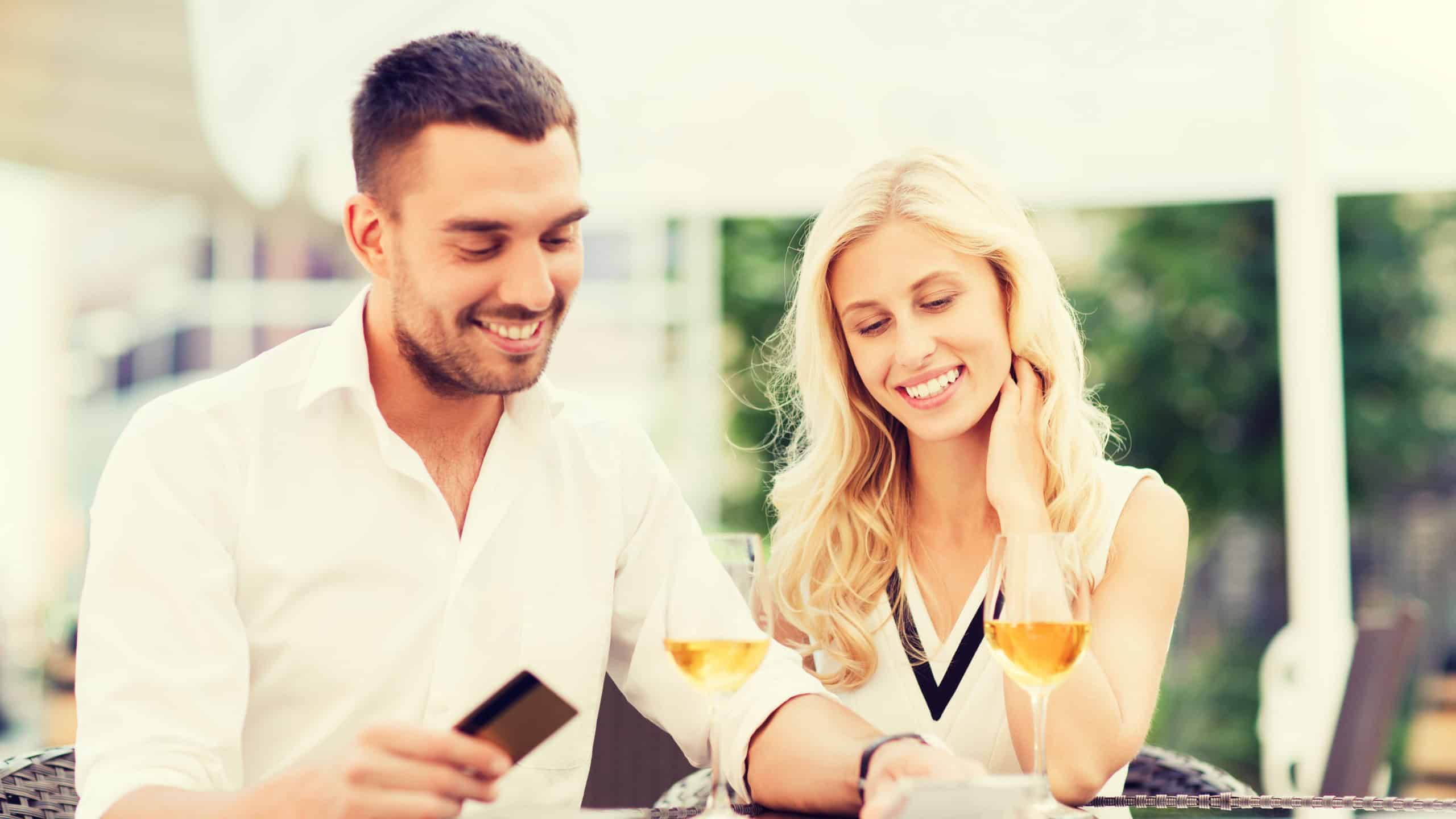 Date, people, payment and relations concept - happy couple with credit card, bill and wine glasses at restaurant terrace
