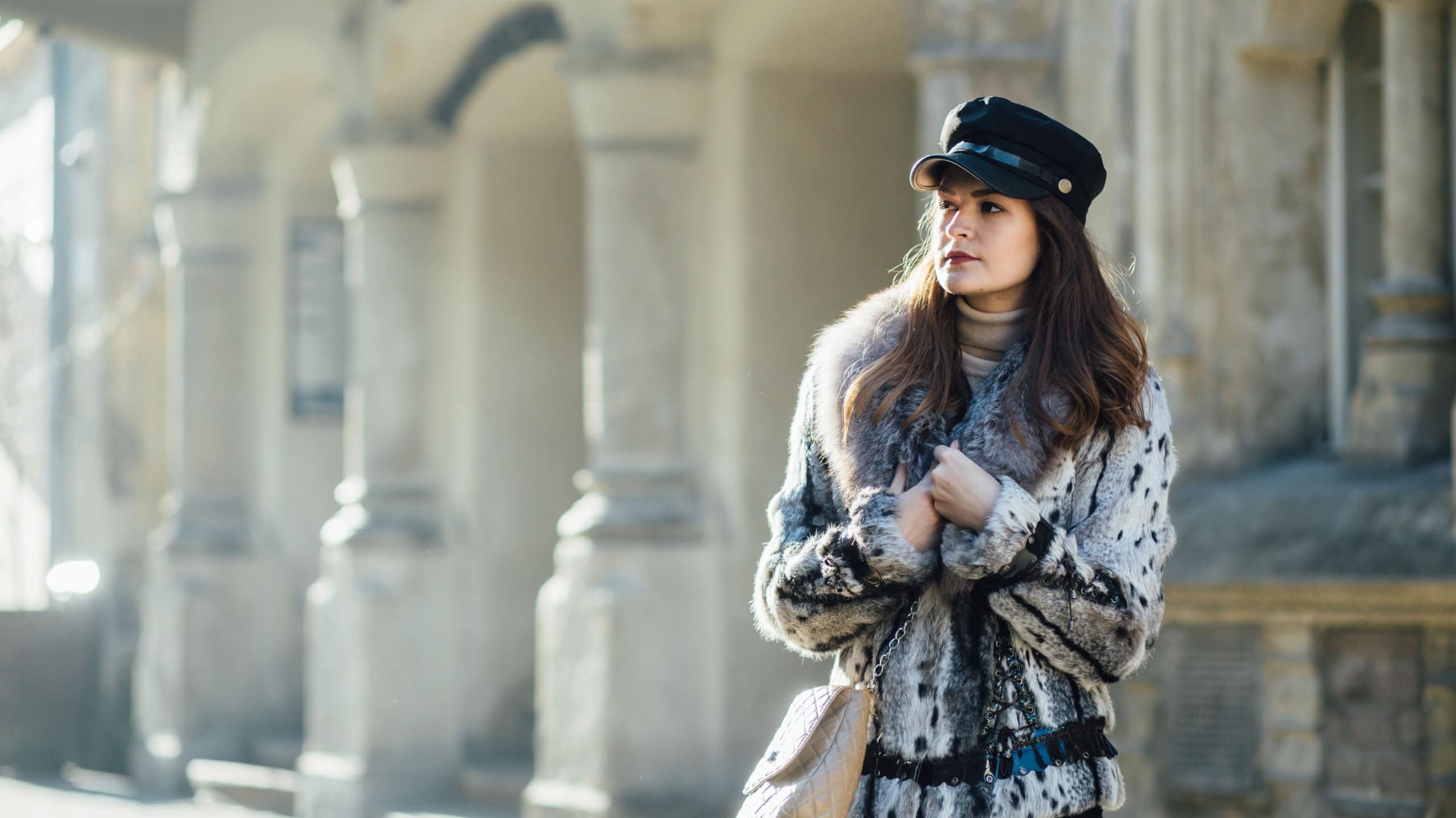 Portrait of young brunette woman in winter walking in old town.