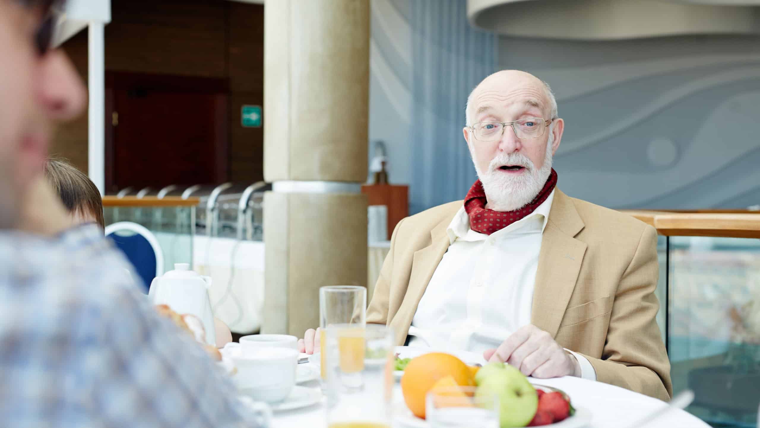 Aged man talking to one of family mambers by table