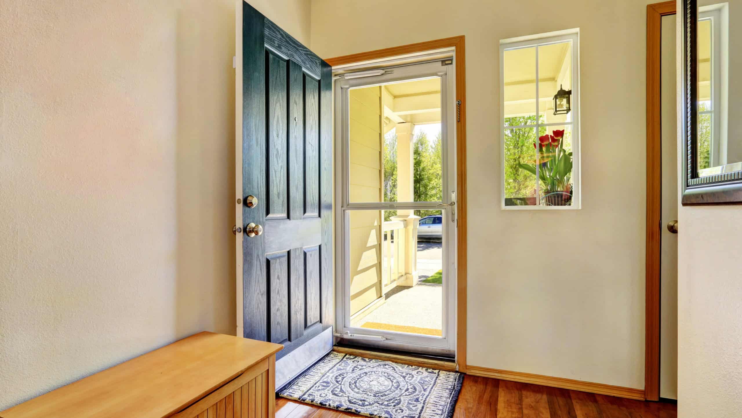 Small foyer with green open front door, laminate floor and wooden bench. Northwest, USA