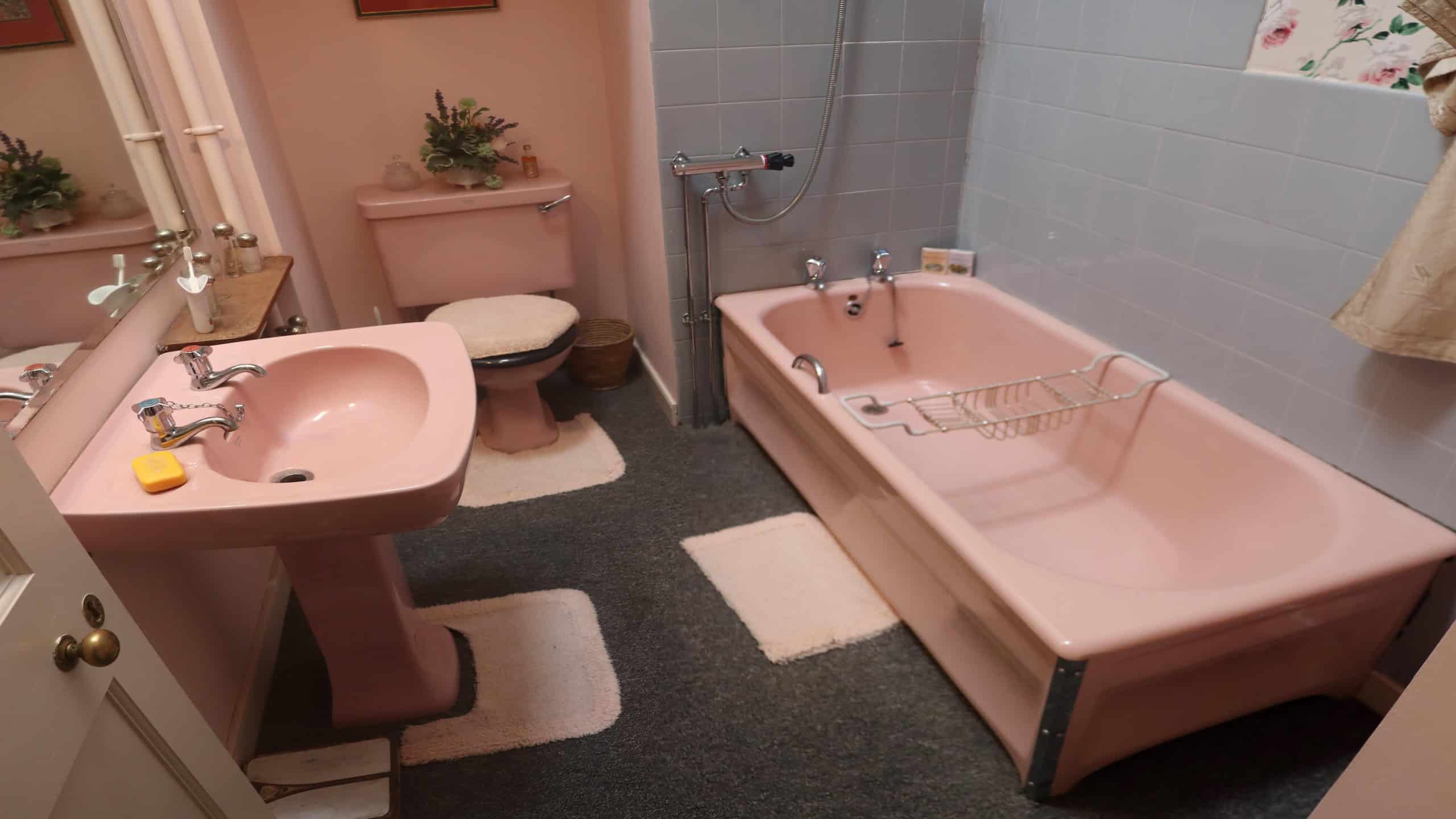 Photograph of a rather splendid/vulgar pink bathroom suite in Skaill House, Orkney, Scotland. The pink bathtub, toilet and sink are complimented marvellously by pink walls, pink mats and a fluffy pink toilet seat cover.