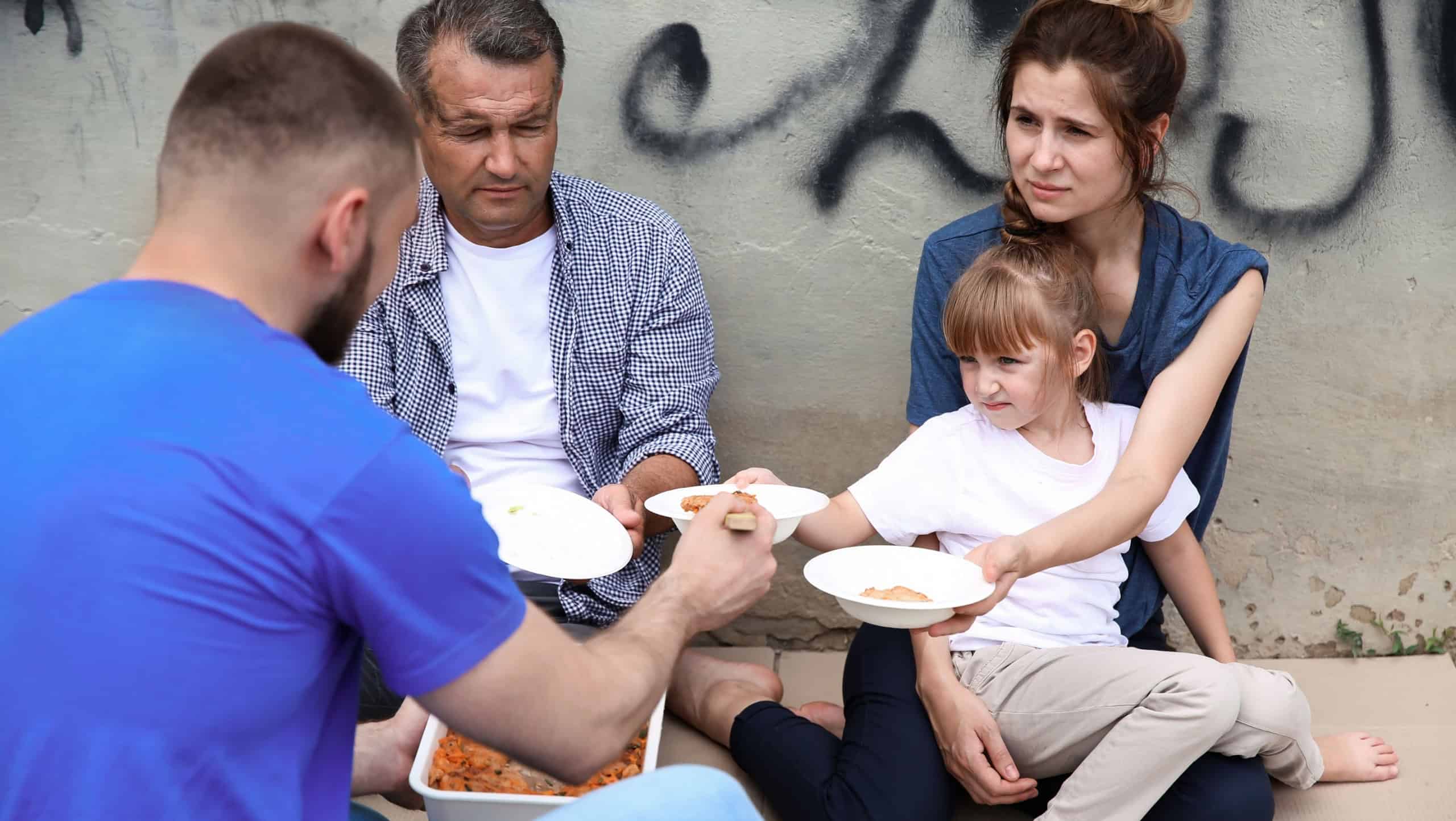 Poor people receiving food from volunteer outdoors