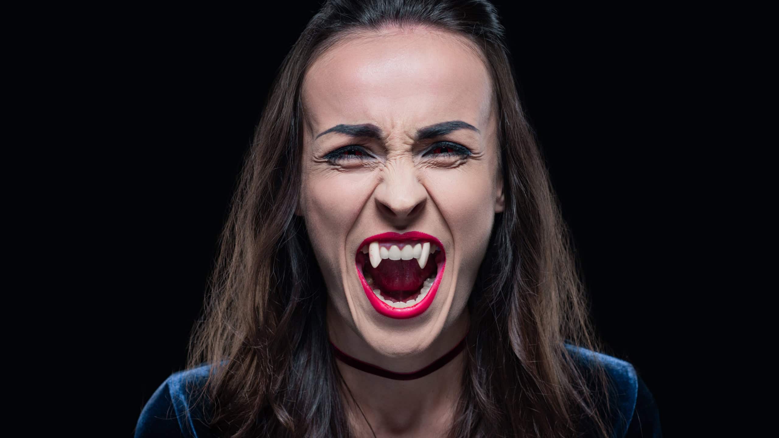 gothic woman showing vampire teeth isolated on black