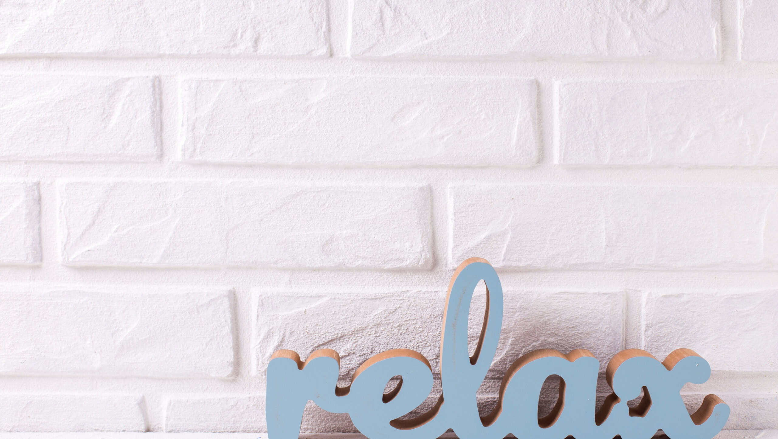Word relax on white textured background near brick wall. Selective focus. Place for text.