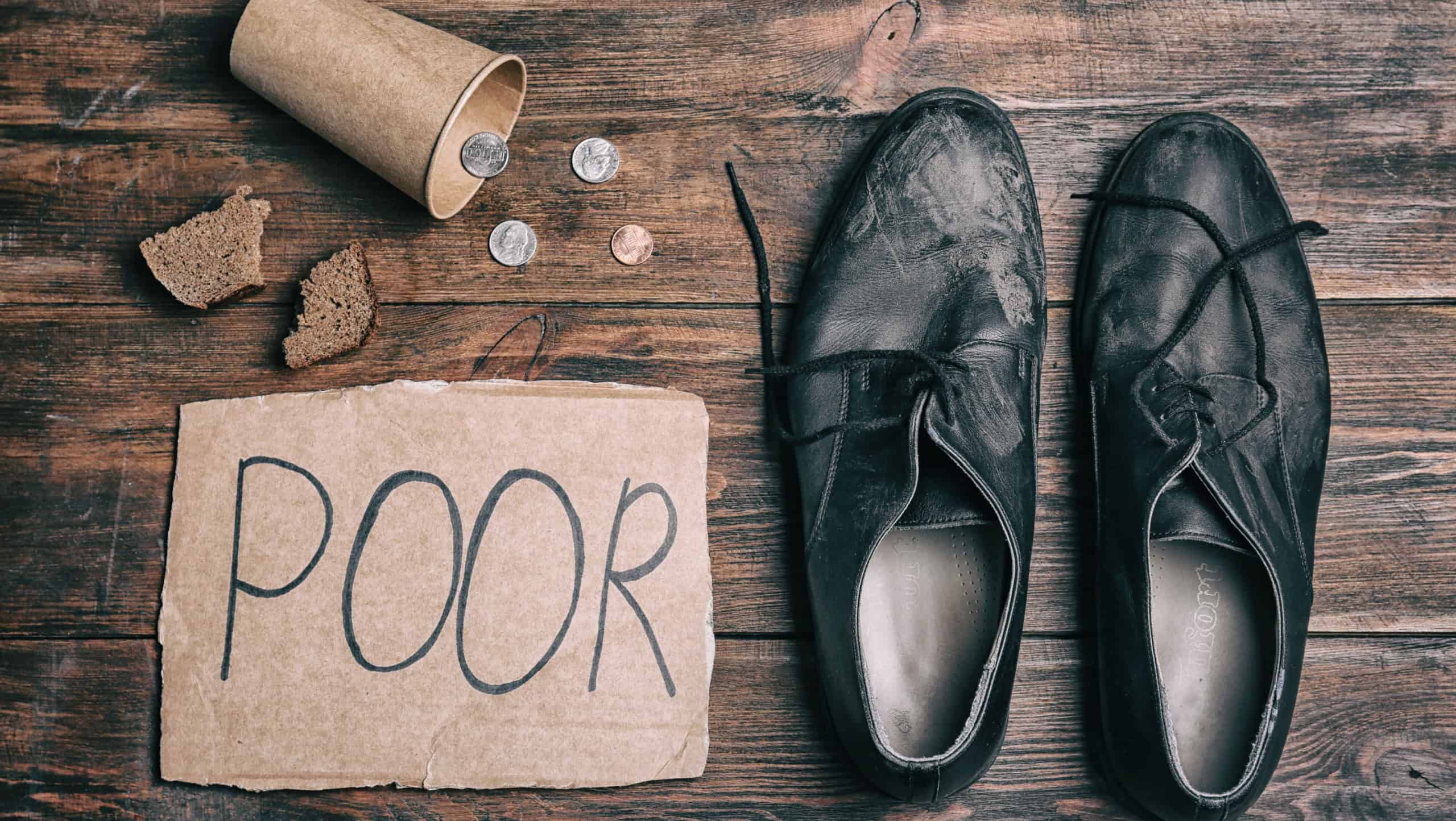 Flat lay composition with word POOR, coins and dirty shoes on wooden background