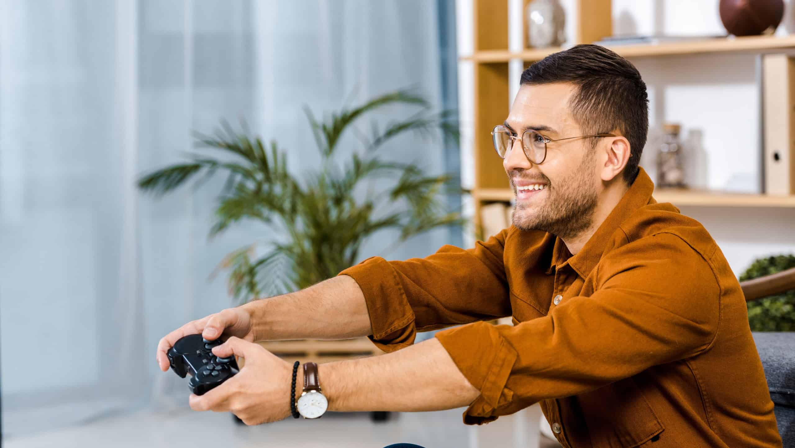 happy man in glasses playing video game at home