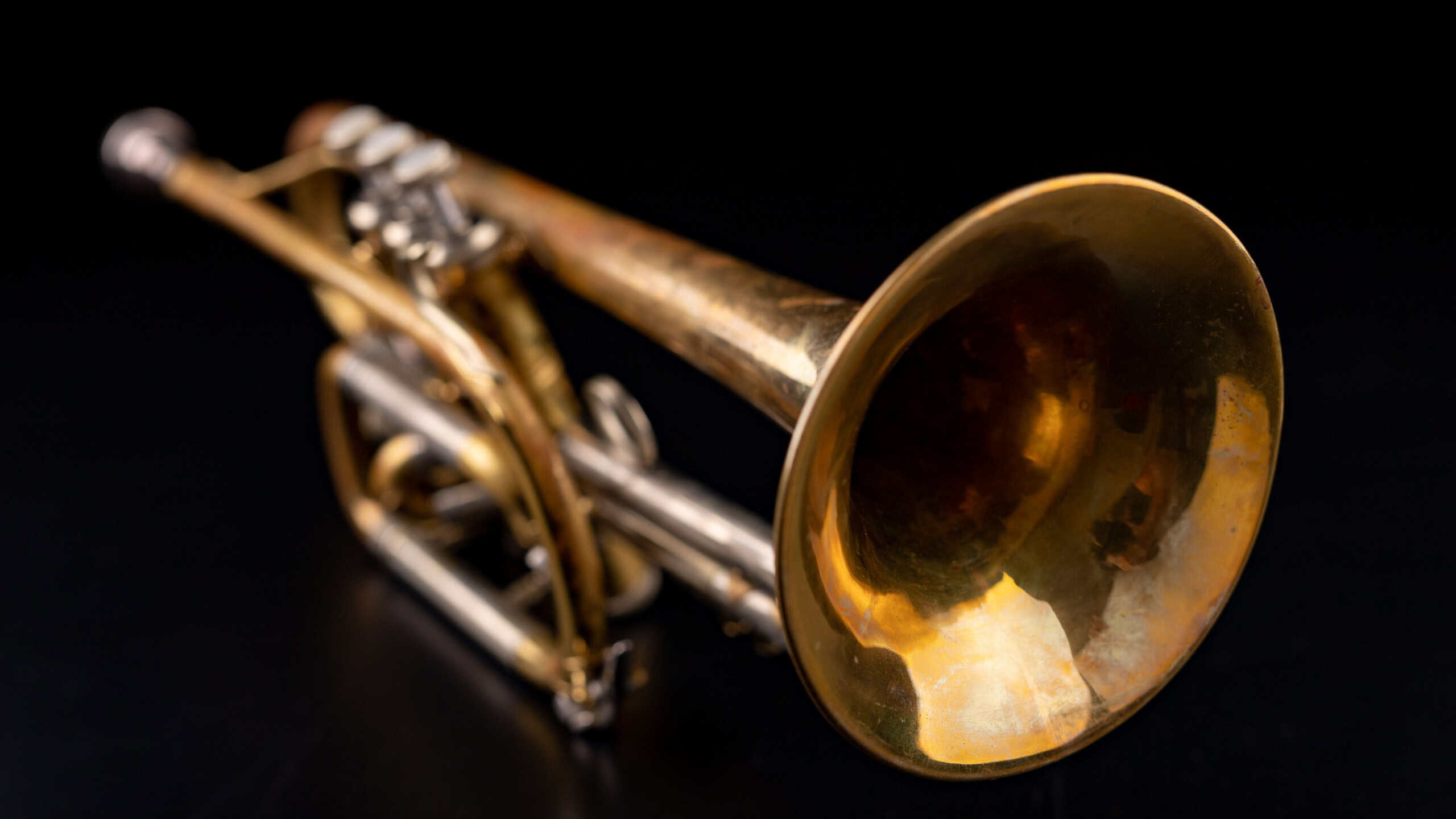 Old trumpet on a dark wooden table. Wind instrument in the old style.