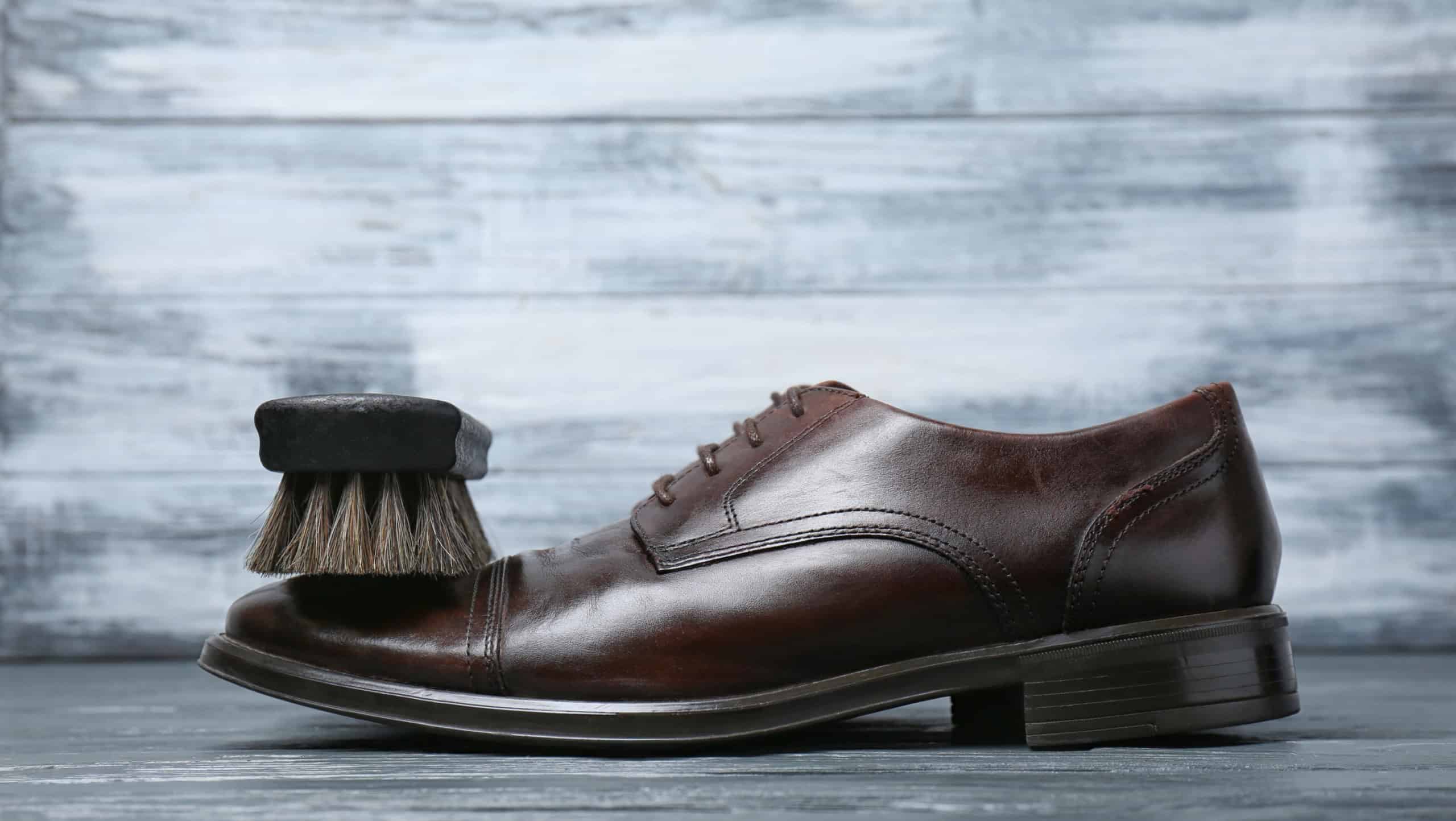 Men's leather shoes and cleaning brush on grey table