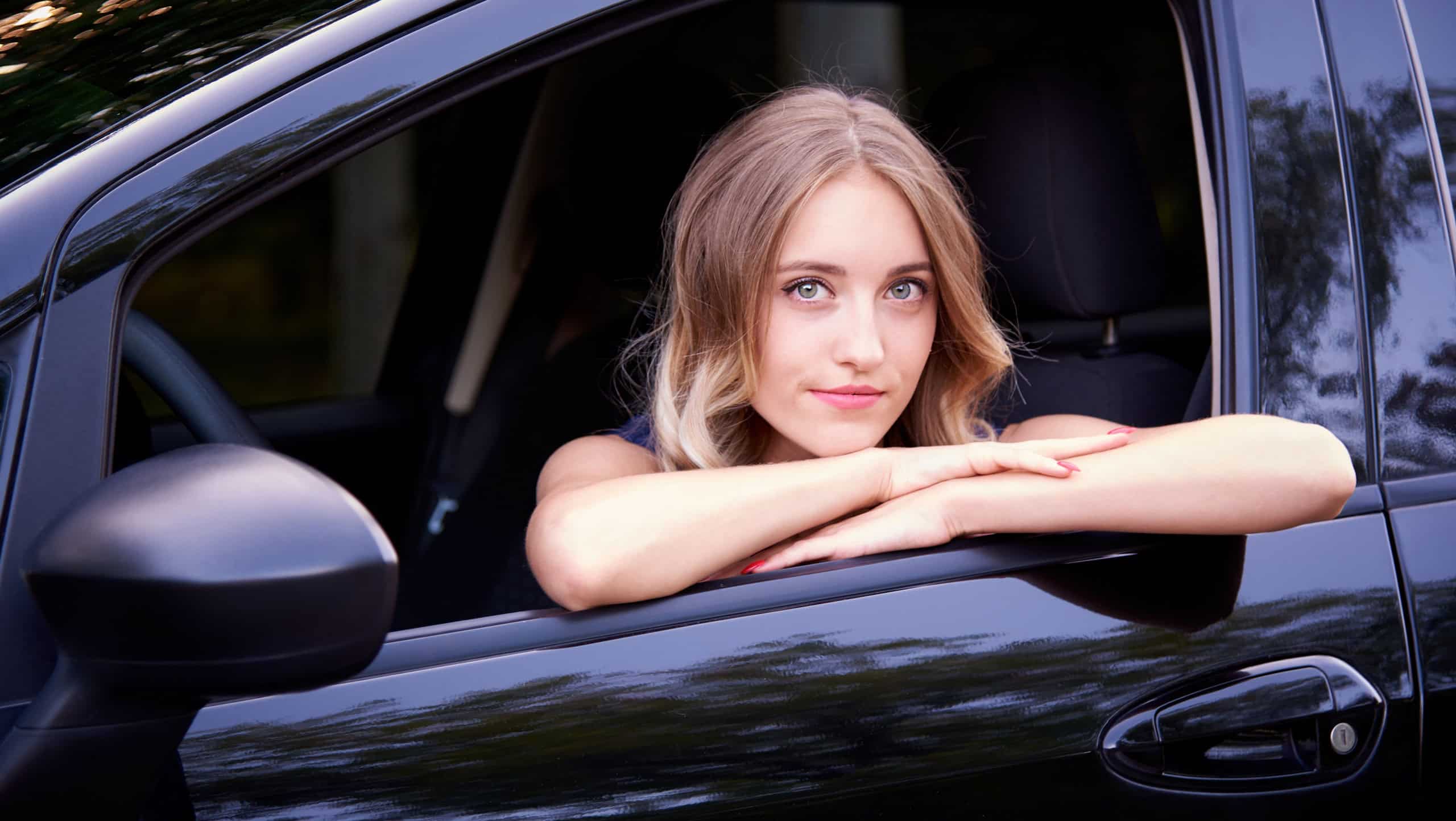 Comely young woman in a black auto.