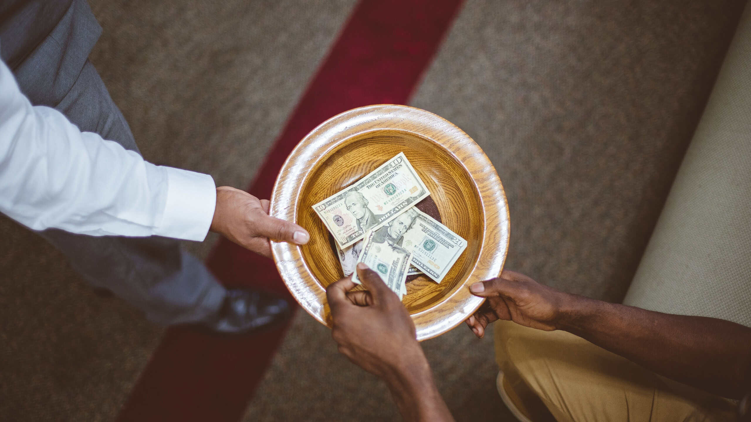 An overhead shot of a person collecting donations for the church with a blurred background