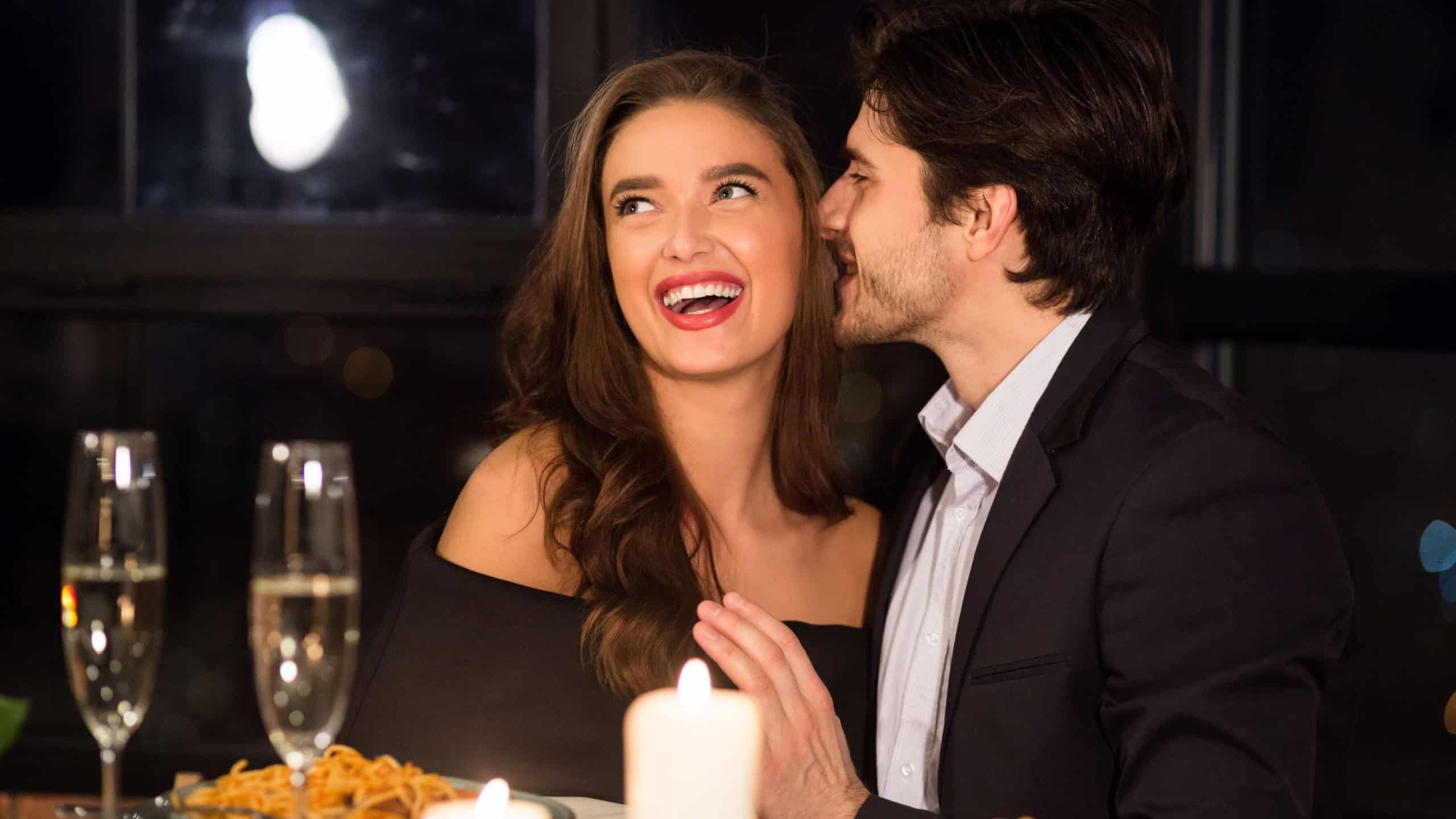 Language of love. Enamored man whispering compliments for his beloved wife during romantic date in restaurant