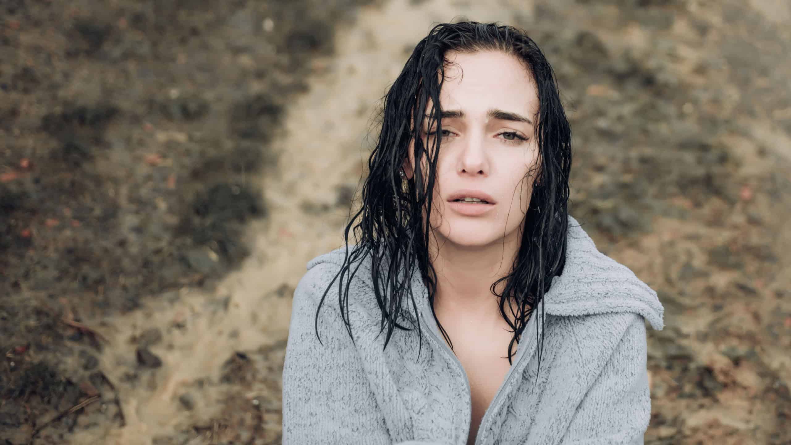 Beautiful girl got wet in the rain and froze. Upset sensual girl with wet hair looking at camera. Adorable attractive woman was caught in a thunderstorm