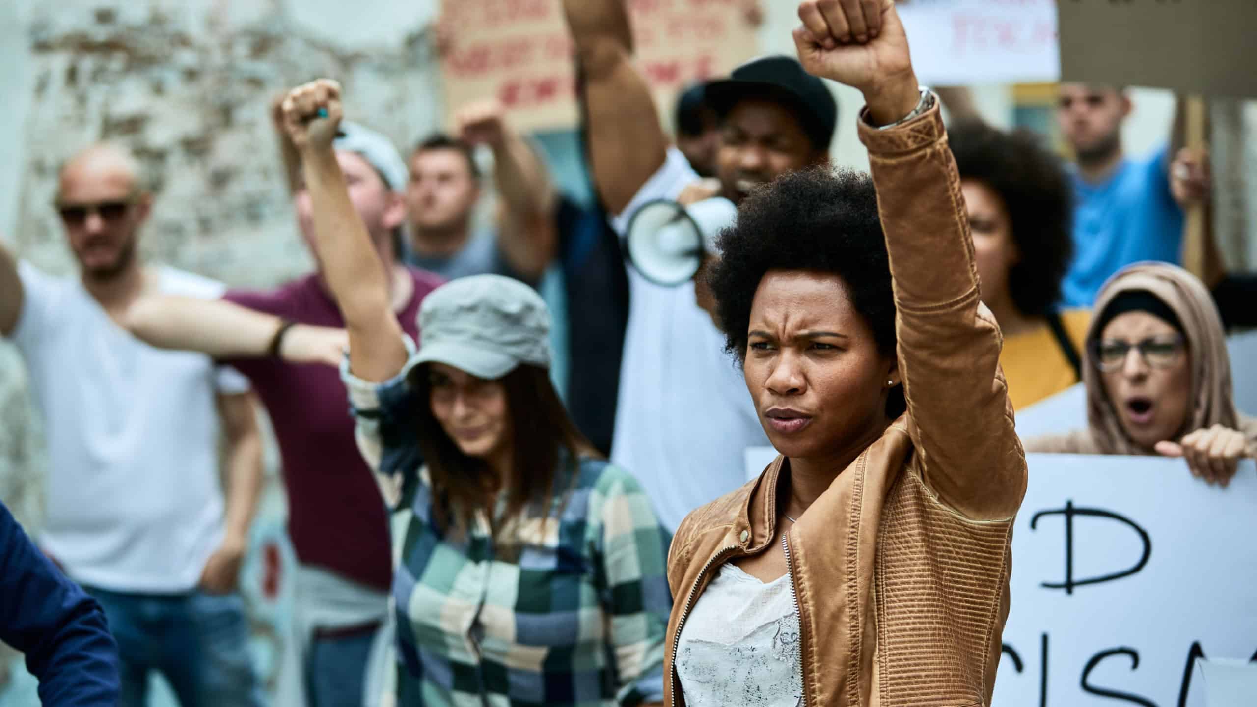 African American woman with raised fist participating in black civil rights demonstrations.