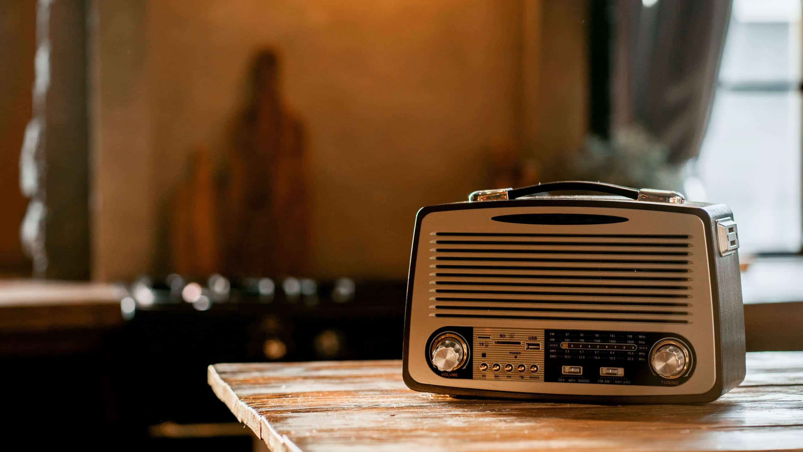 A stylish retro radio player stands on a wooden table. stylish kitchen in the village, daylight from the window.