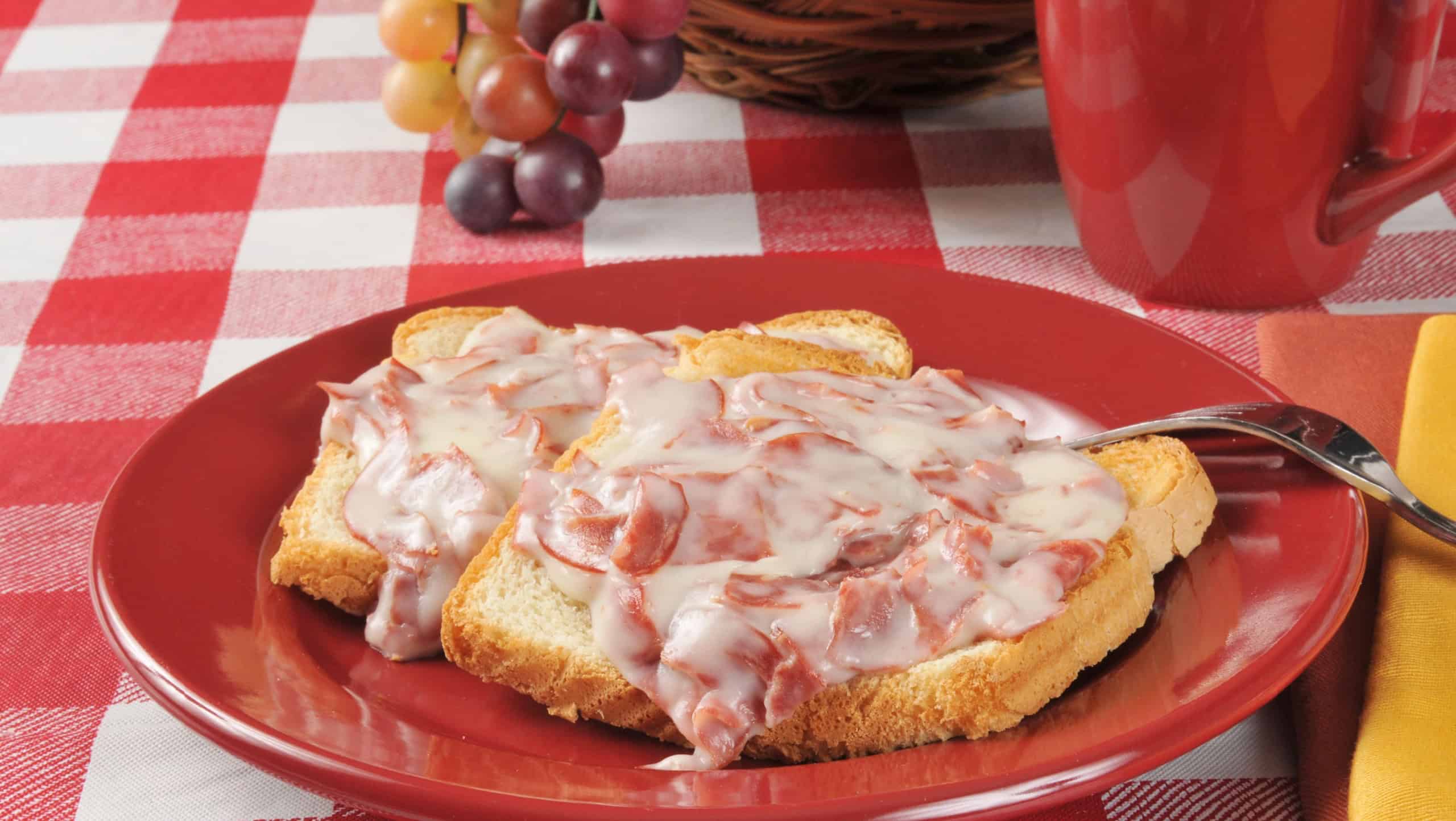 A plate of creamed chipped beef on toast with a drink