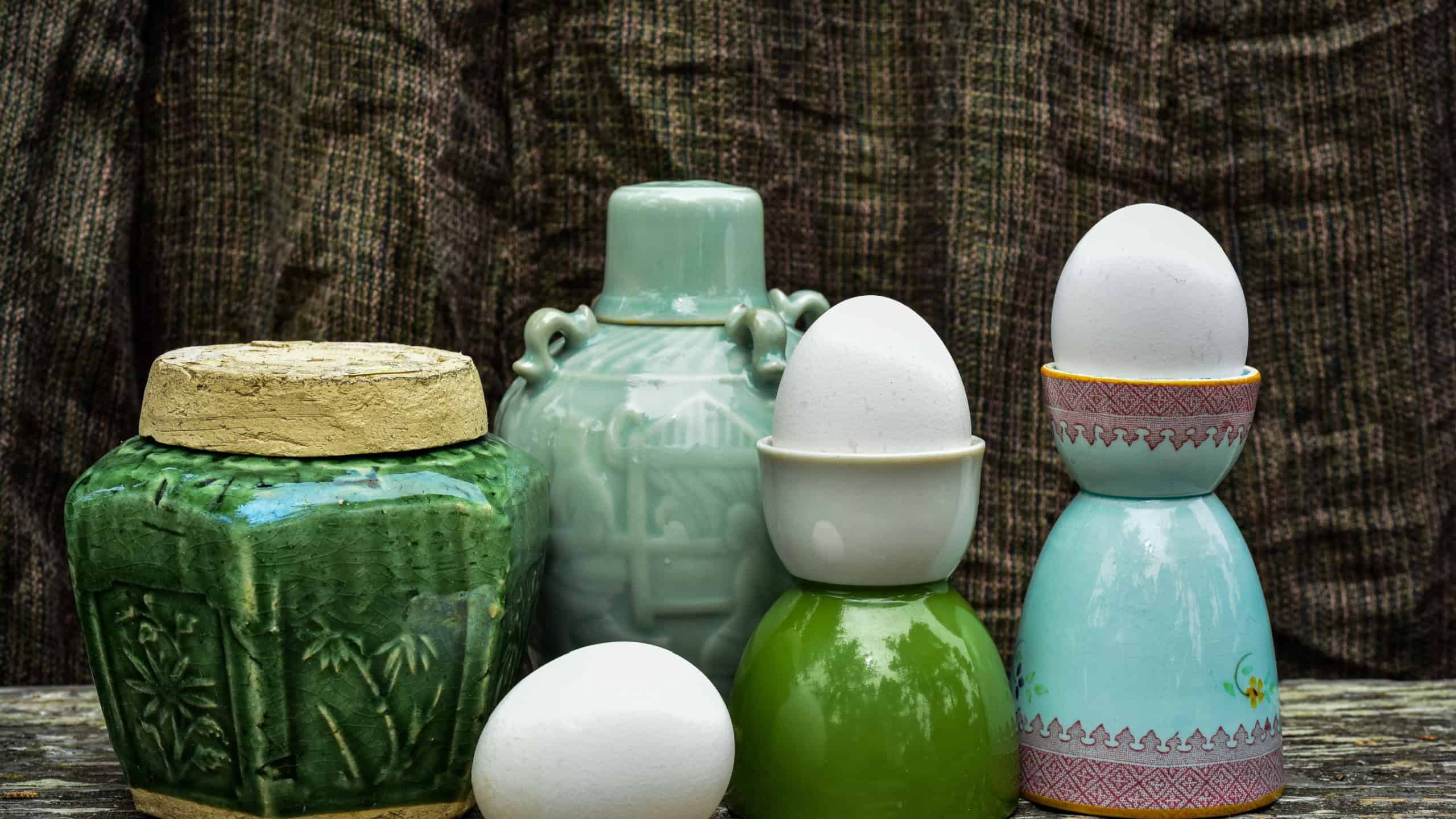 egg cup coddlers holding white shelled soft boiled eggs in still life