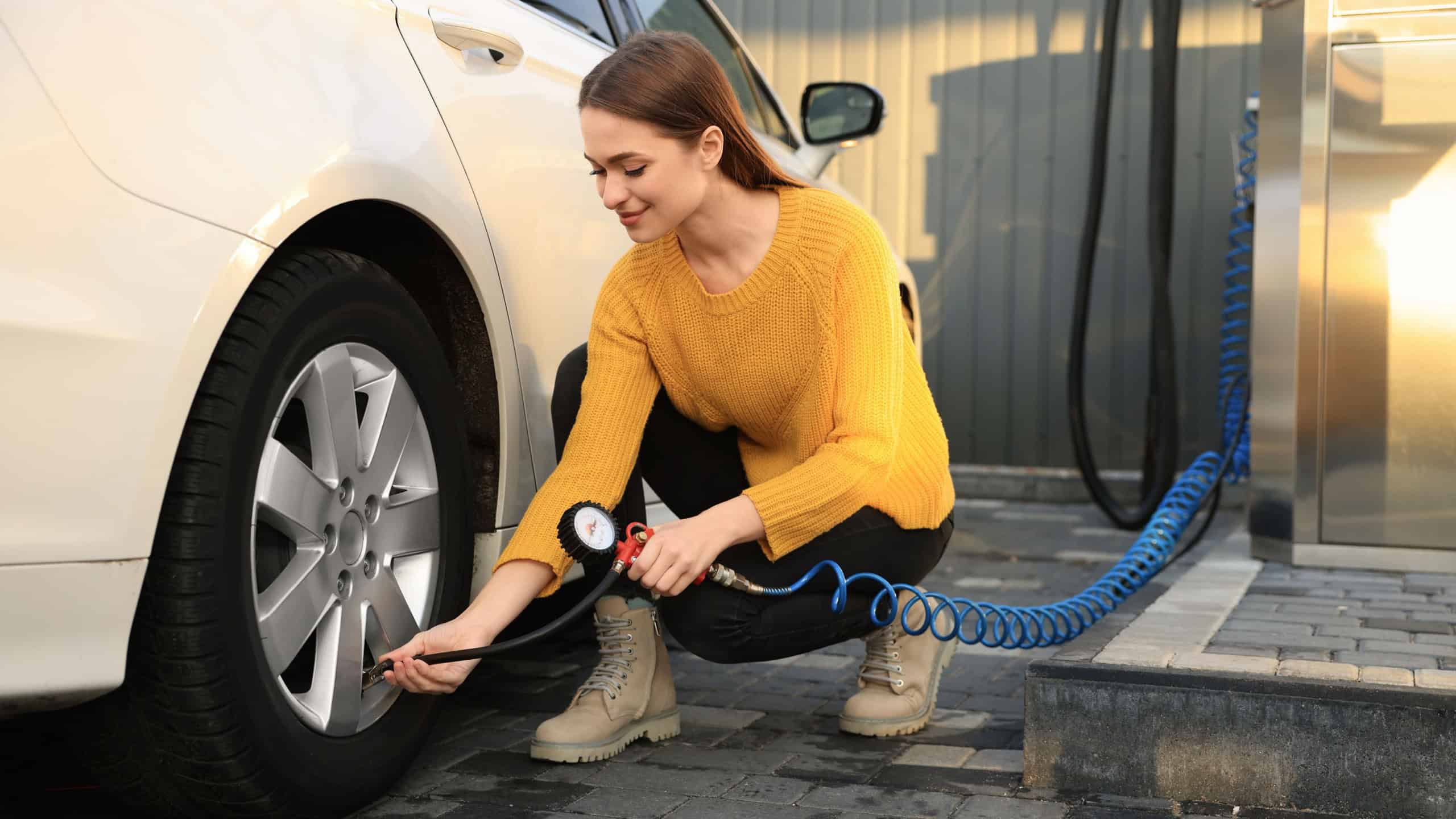 Young woman inflating tire at car service