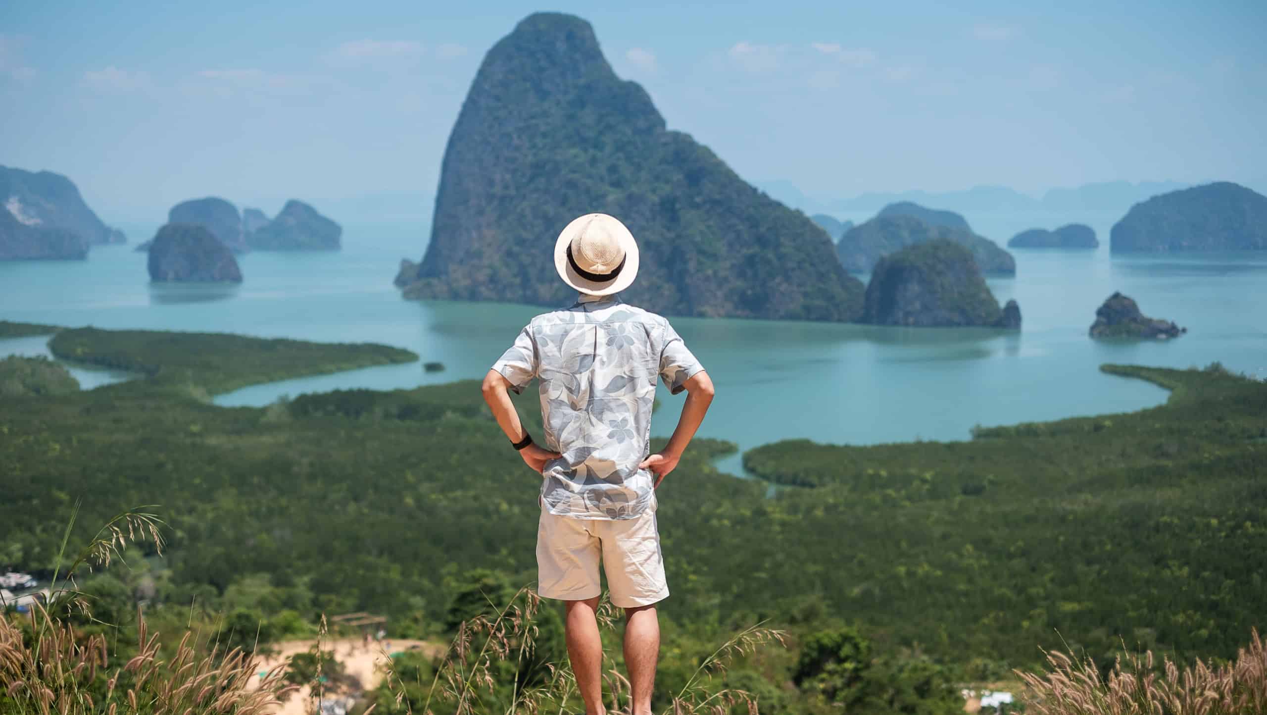 Happy traveler man enjoy Phang Nga bay view point, alone Tourist standing and relaxing at Samet Nang She, near Phuket in Southern Thailand. Southeast Asia travel, trip and summer vacation concept