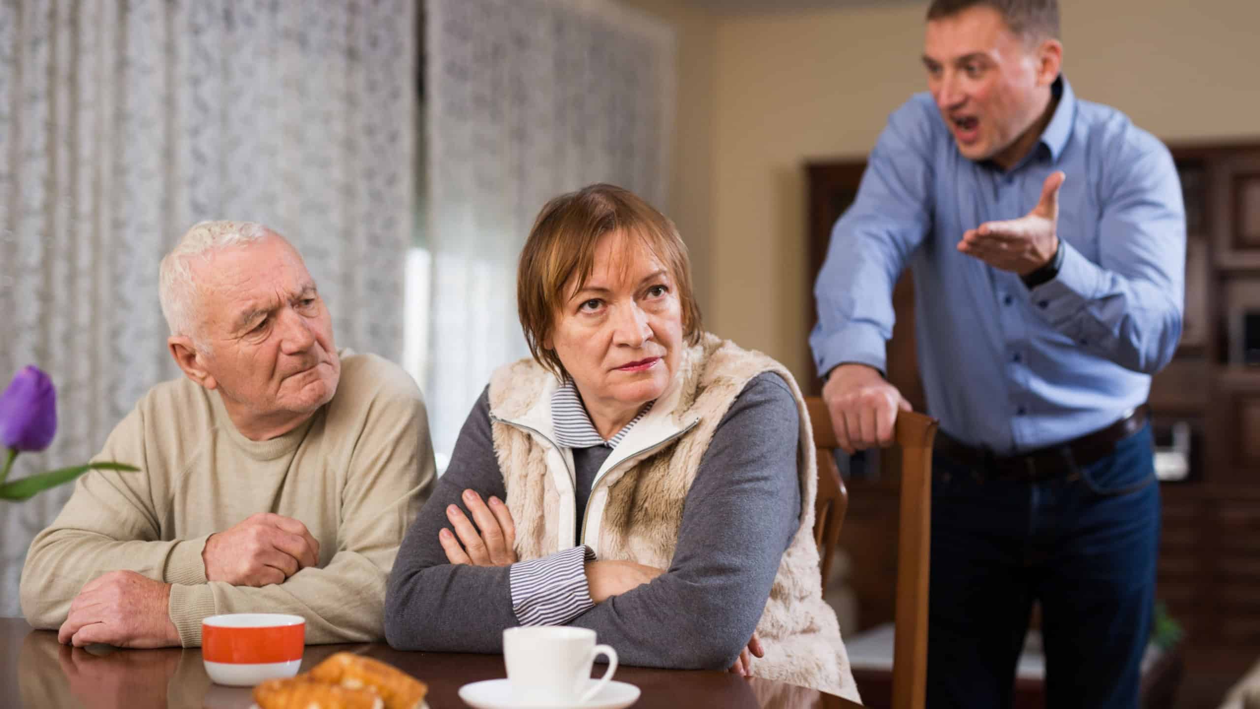 Adult annoyed man scolding his senior parents at home