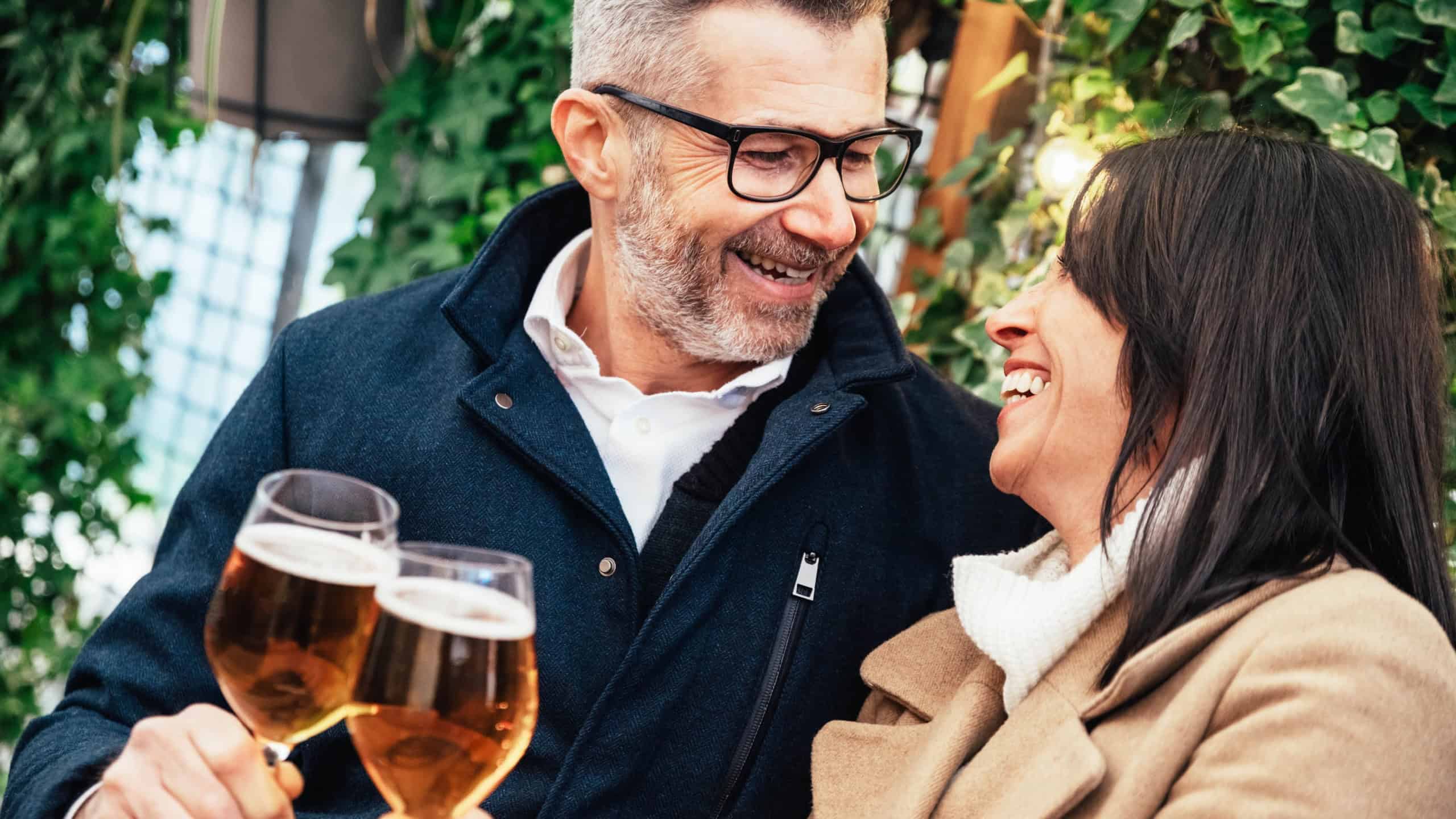 Mature couple having fun drinking beer at cafe bar restaurant - Husband and wife hanging out enjoying happy hour at brewery pub