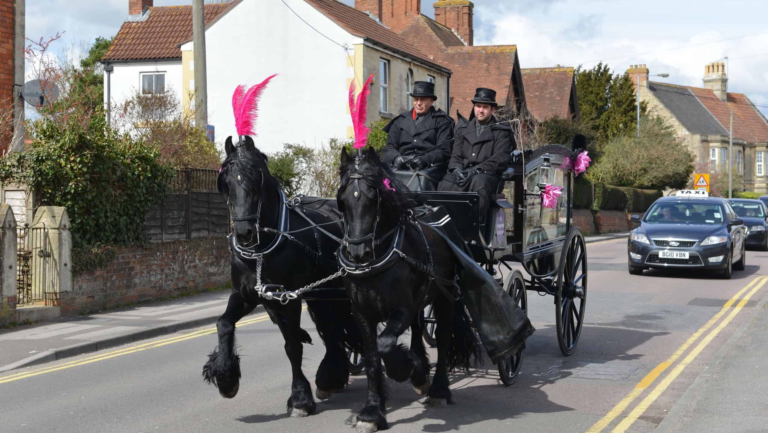 A horse drawn funeral carriage passes along a town street on March 30, 2016 in Trowbridge, UK.