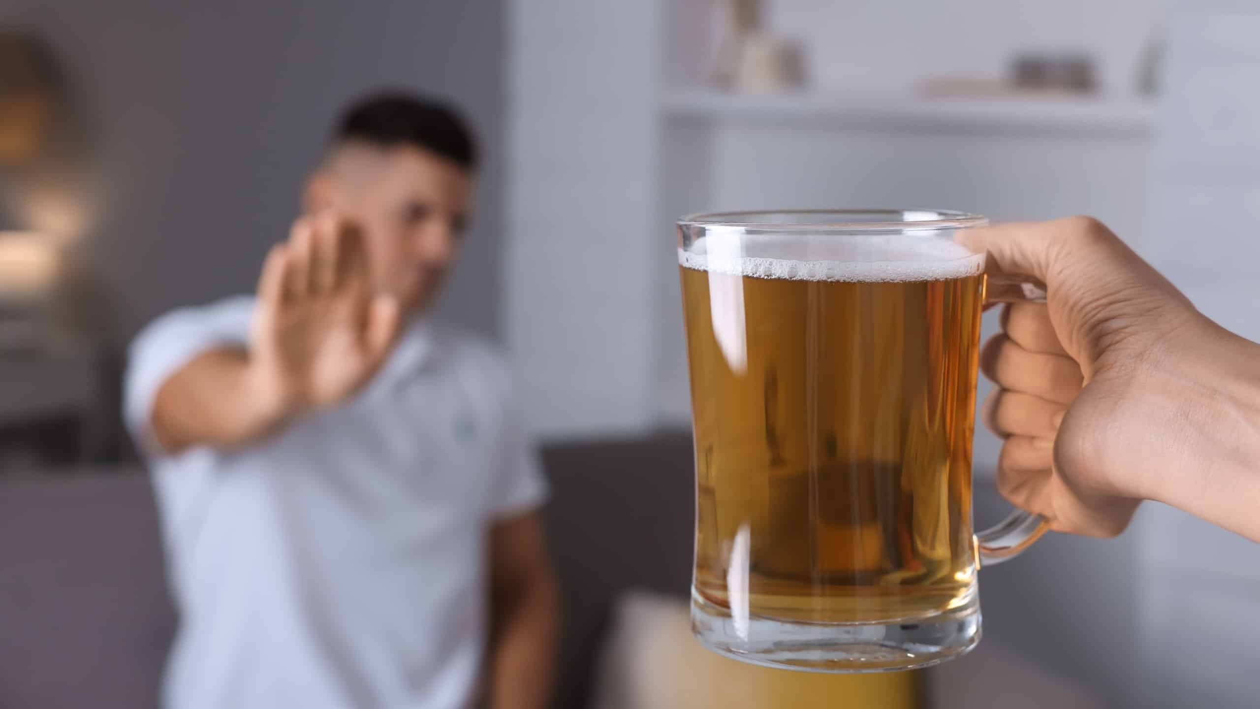 Person holding a beer mug with a hand gesture to decline.