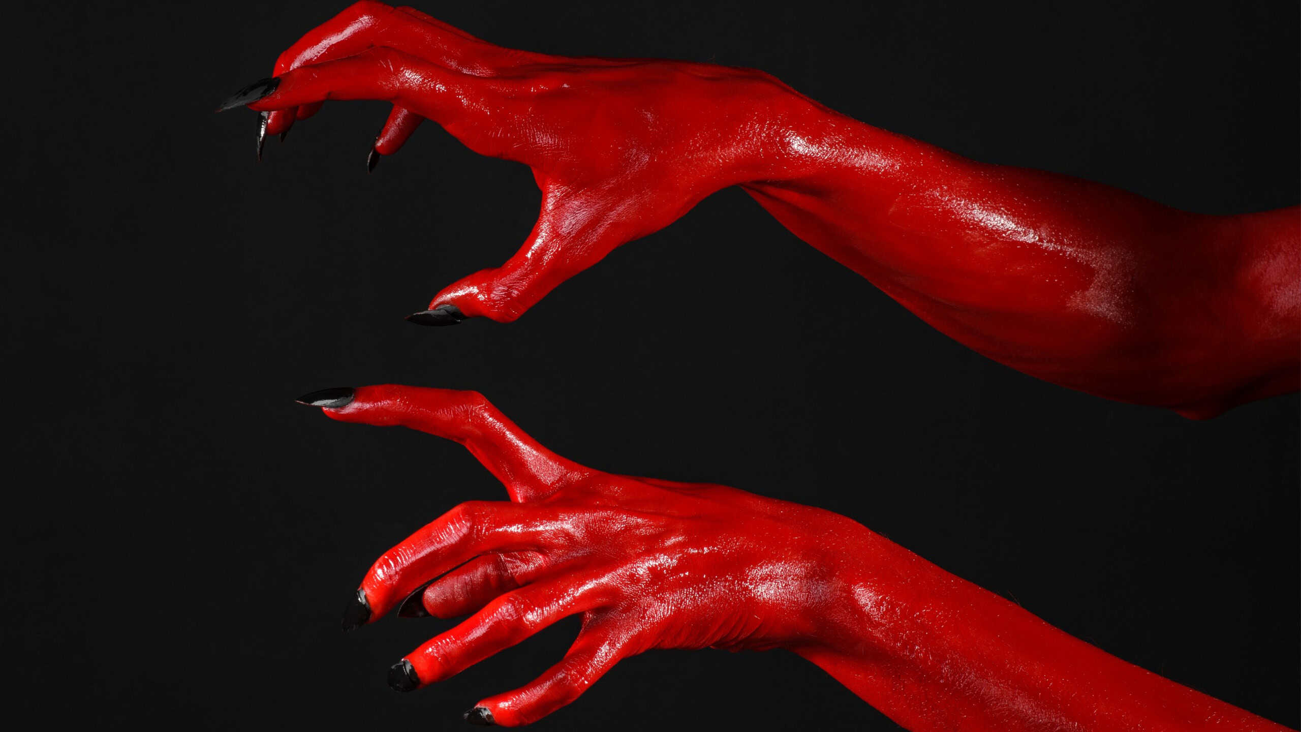 Red Devil's hands, red hands of Satan, Halloween theme, black background, isolated