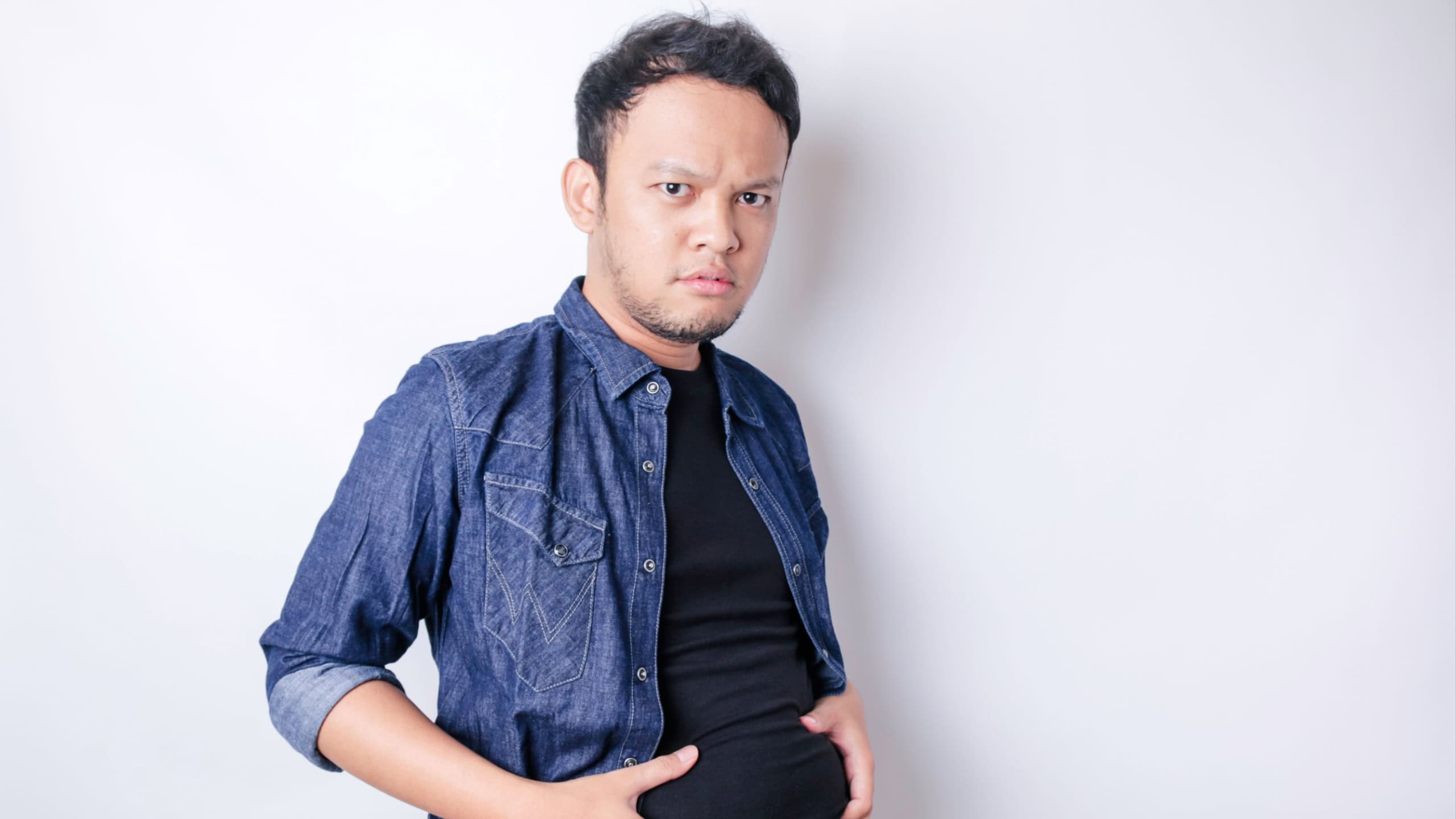A portrait of insecure Asian fat man is holding the fat around his waist