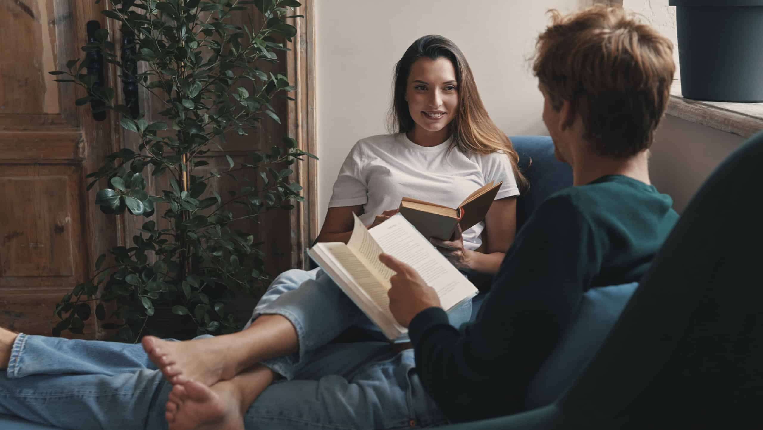 Happy young couple reading books while relaxing at home together