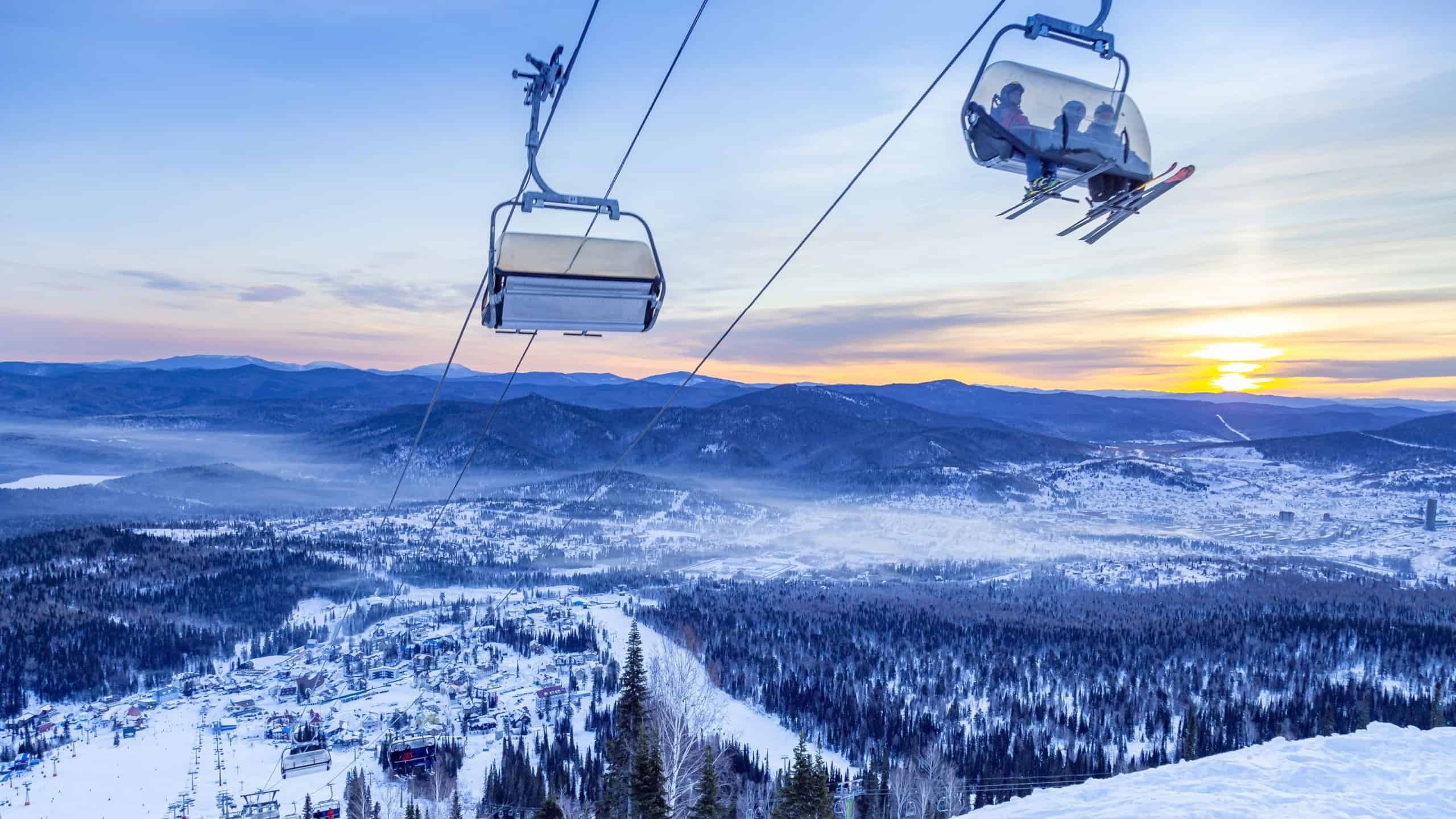 View from mount peak on Sheregesh ski resort and Altai mountains or Gornaya Shoria. Active winter rest, skiers and snowboarders on ski slope and Ski lift, beautiful nature and sport leisure.