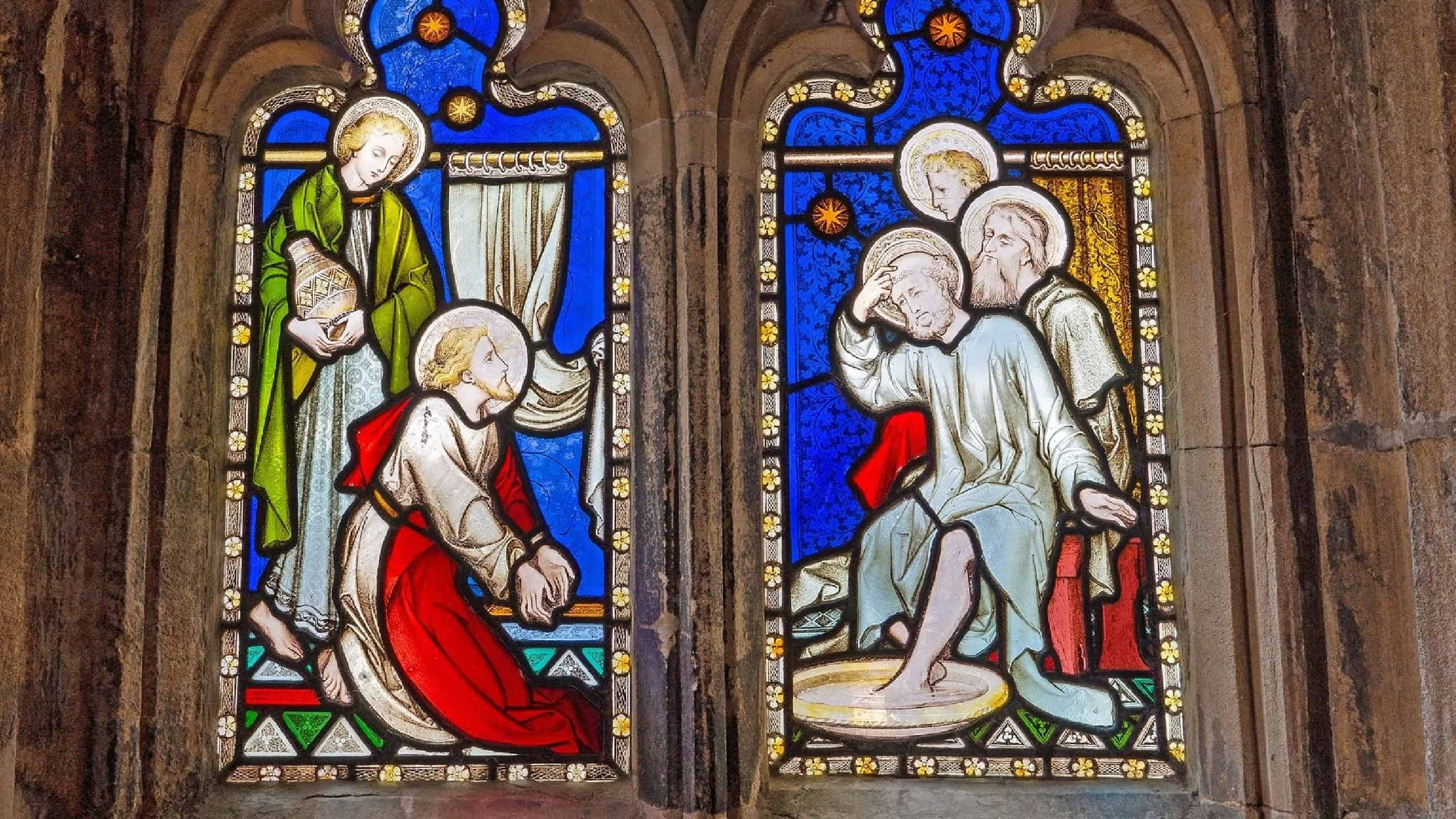 The stained glass window illustrates the biblical story of Christ washing his disciples feet at the Last Supper.