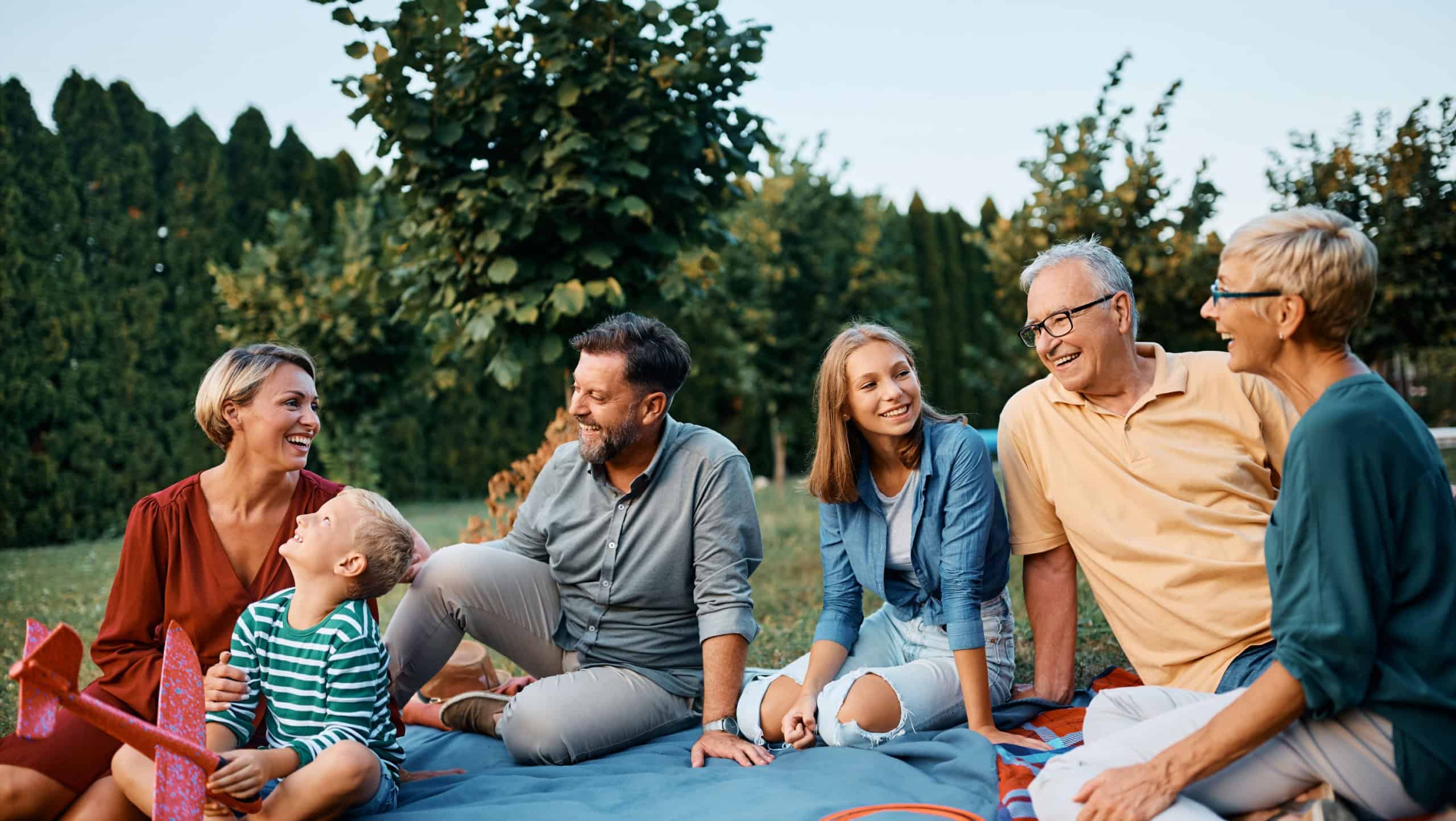 Happy extended family enjoying in conversation while relaxing in their backyard. Copy space.