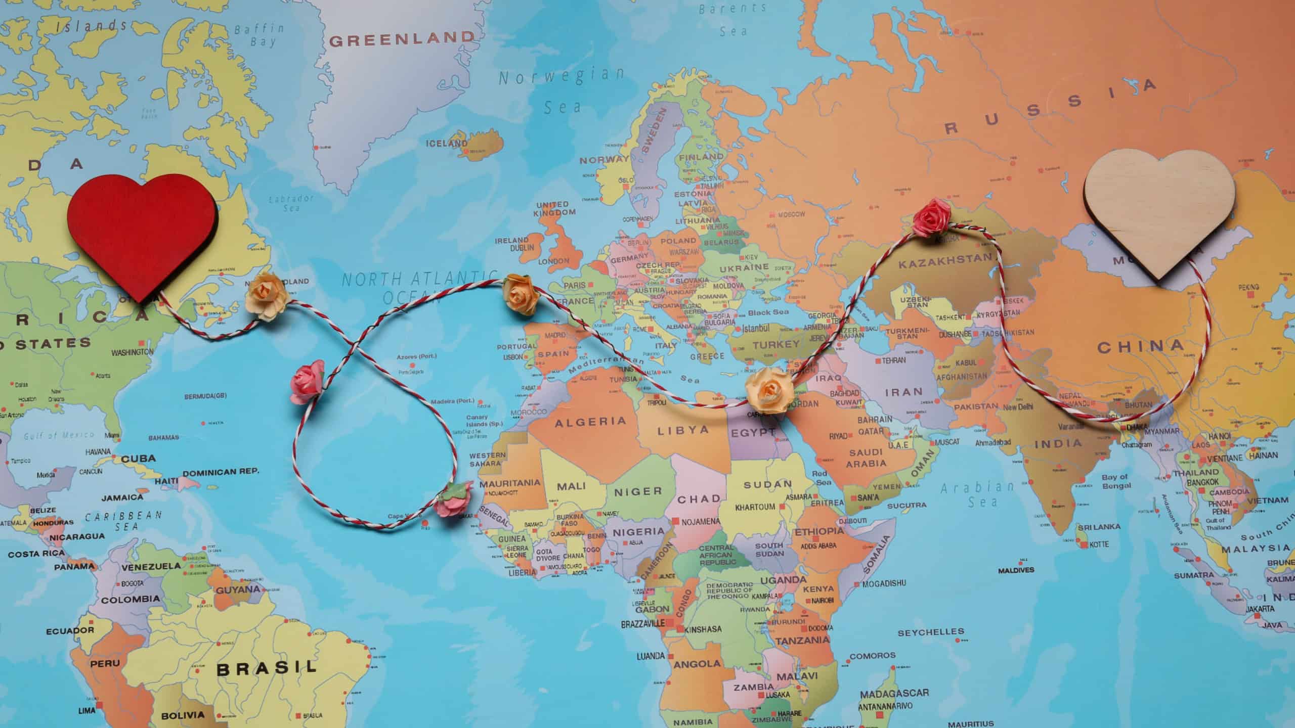 Decorative cord with hearts on world map symbolizing connection in long-distance relationship