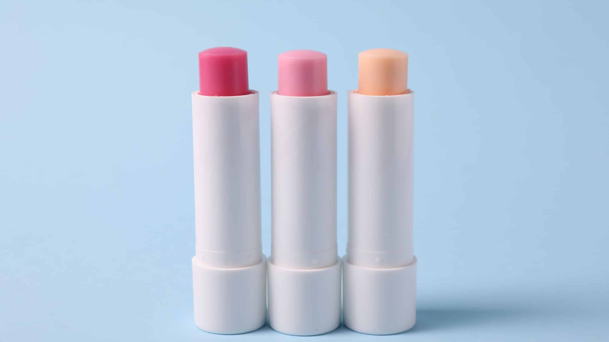 Different lip balms on light blue background