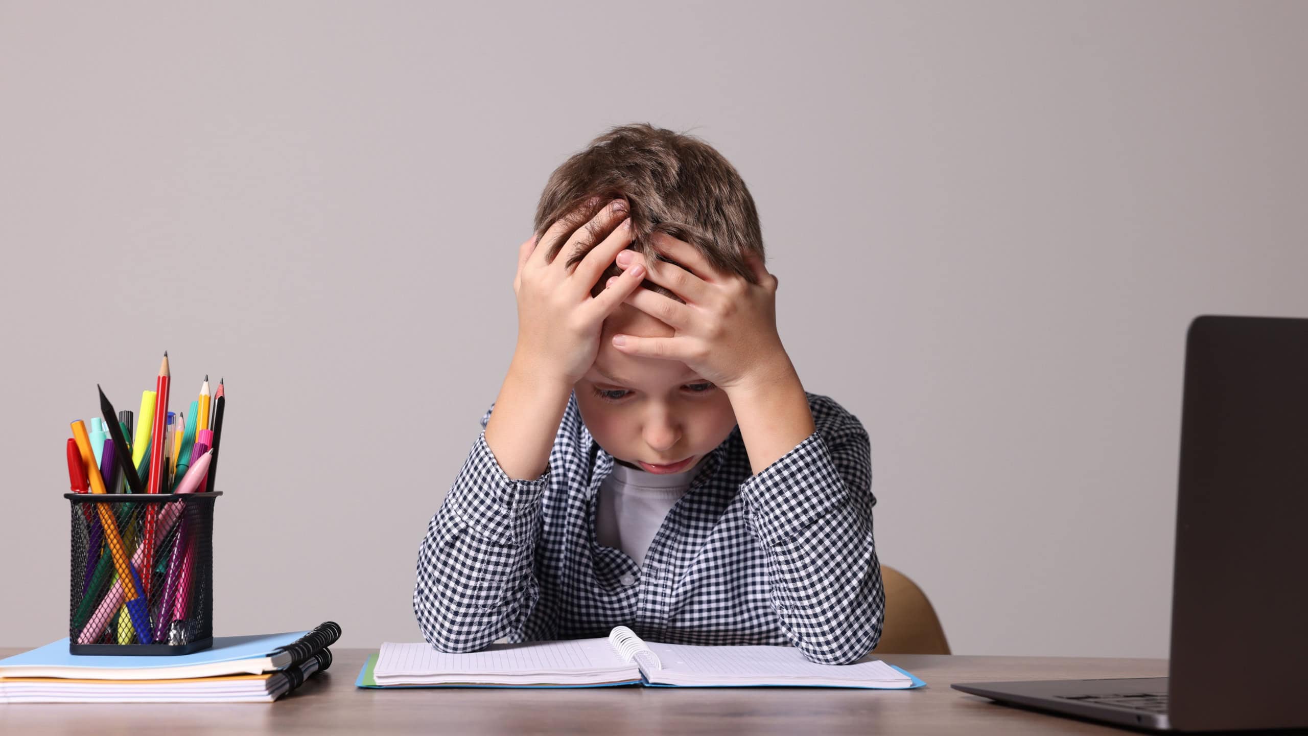 Little boy with stationery suffering from dyslexia at wooden table
