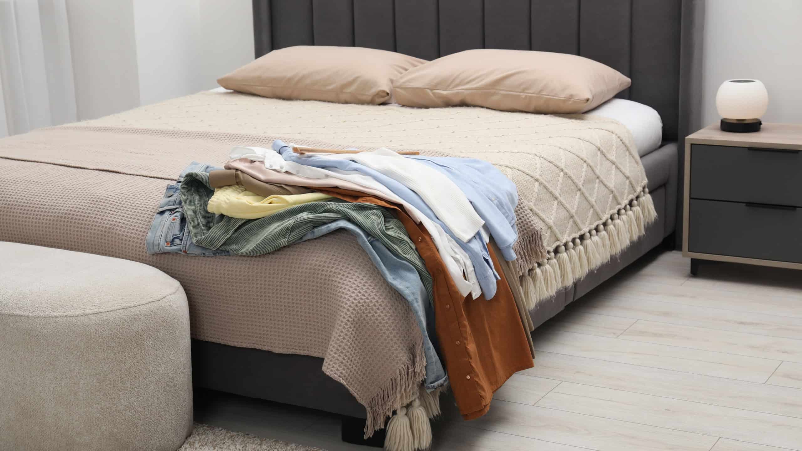 Pile of different clothes on bed at home